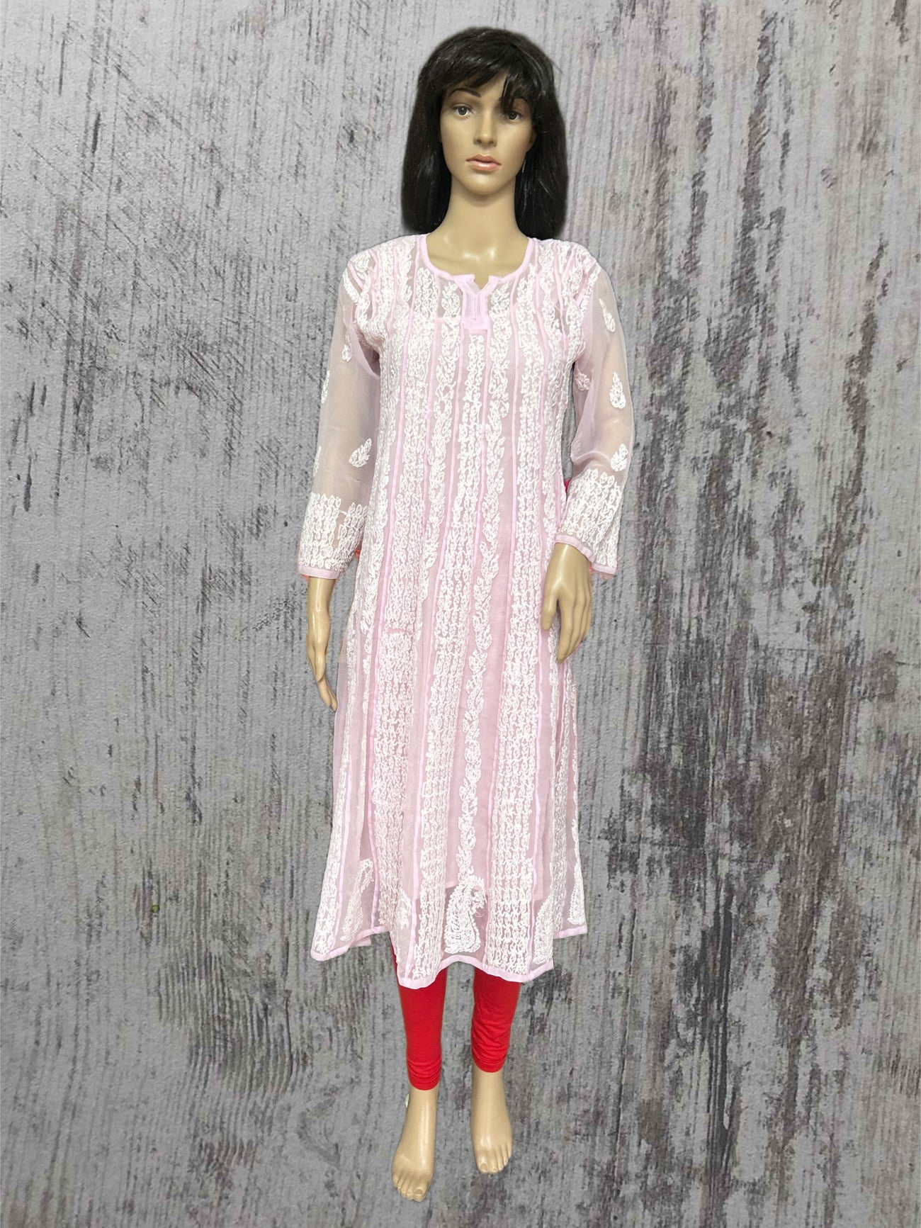 Mannequin wearing a light pink traditional outfit with red leggings against a textured gray background