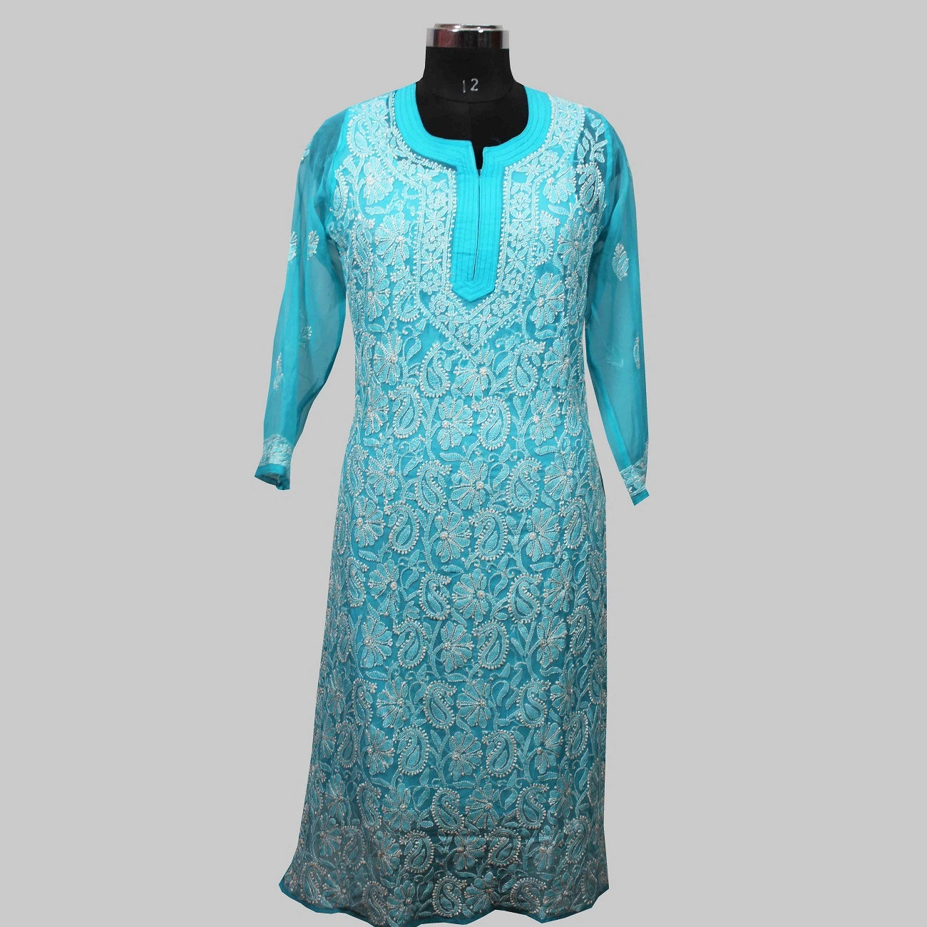 Turquoise embroidered dress on a mannequin against a gray background