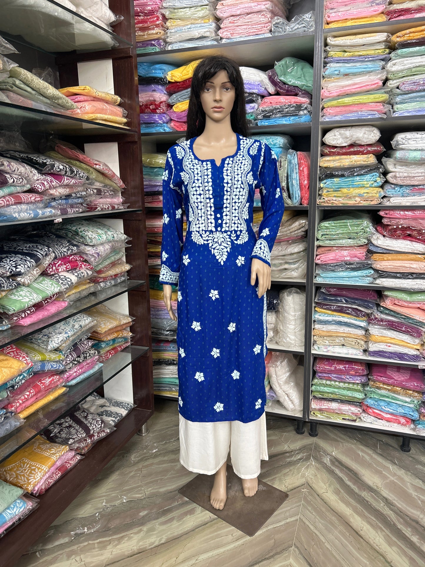 lucknowi chikankari Mannequin wearing a blue dress with white patterns in a fabric store.