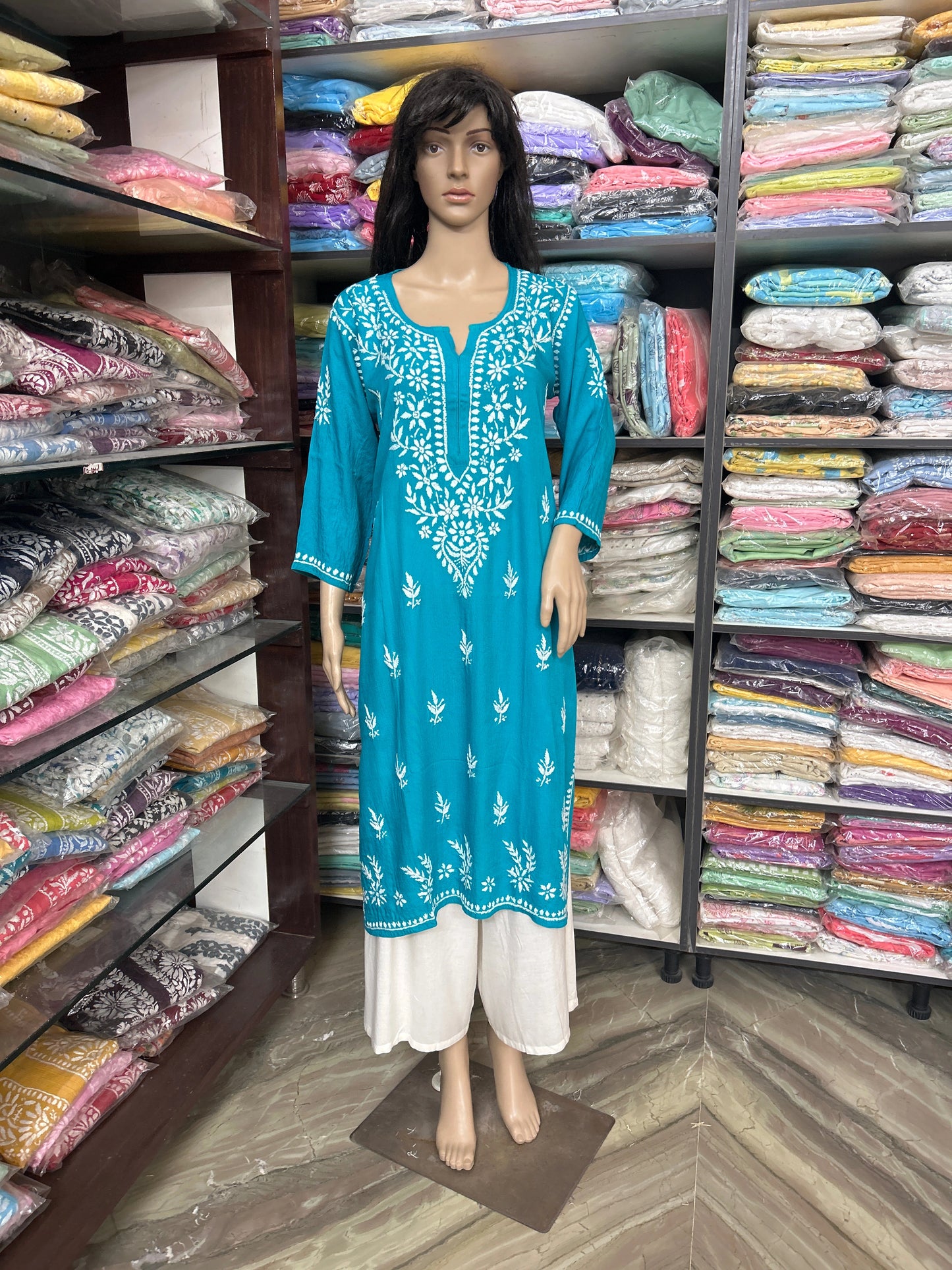 Mannequin wearing a blue embroidered dress in a fabric store