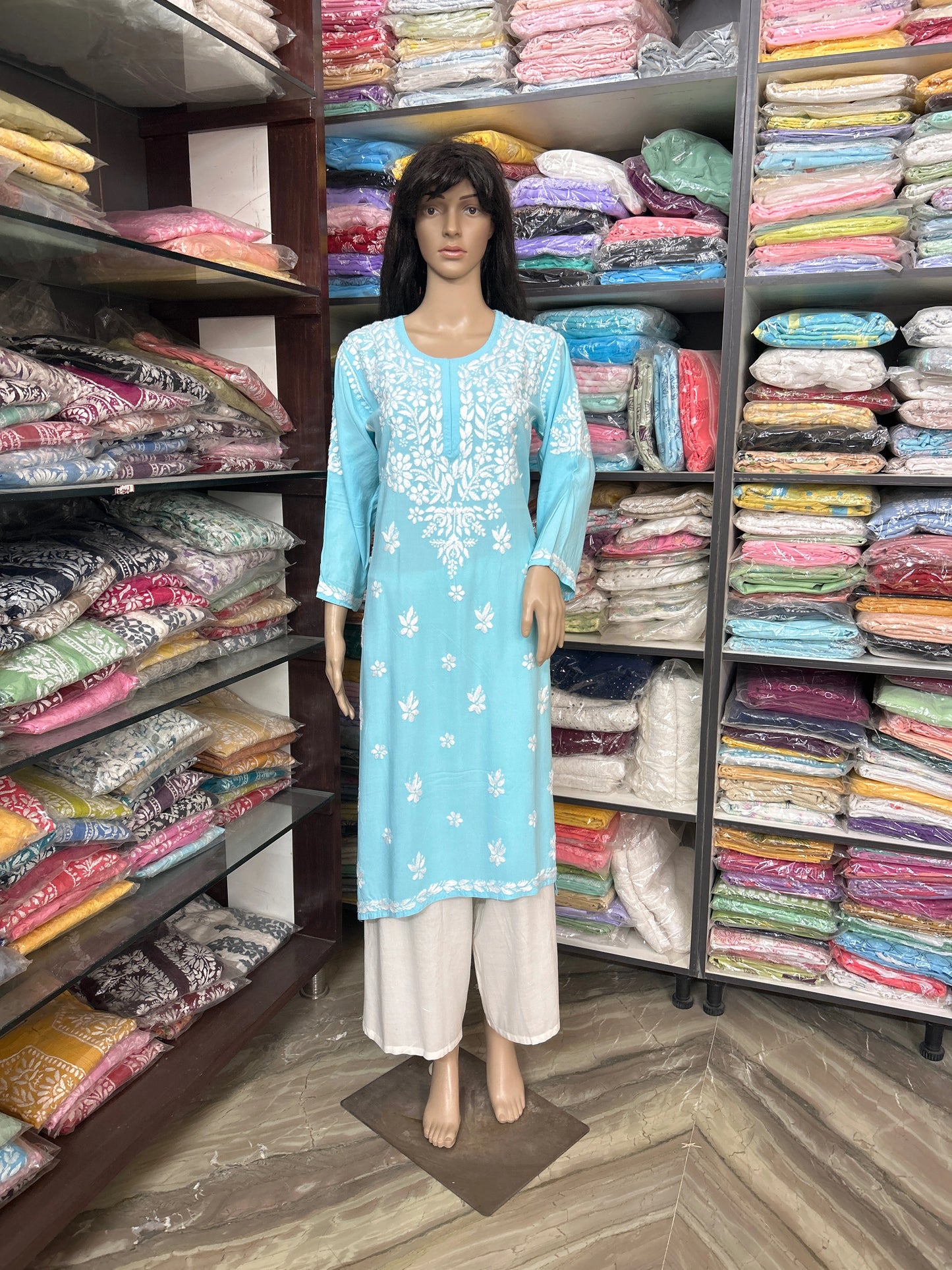 Mannequin wearing a light blue embroidered kurta with white pants in a fabric store.
