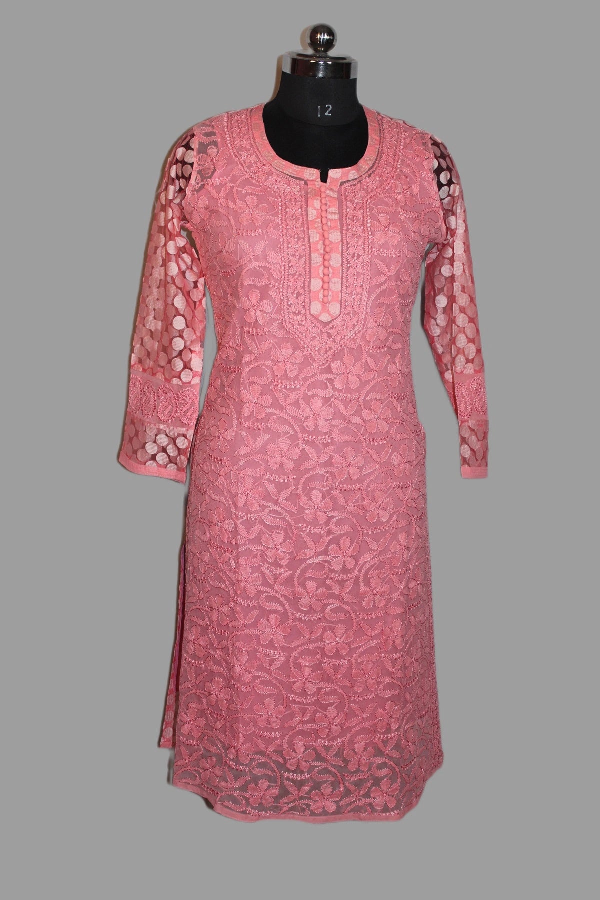 Pink embroidered dress on a mannequin against a gray background