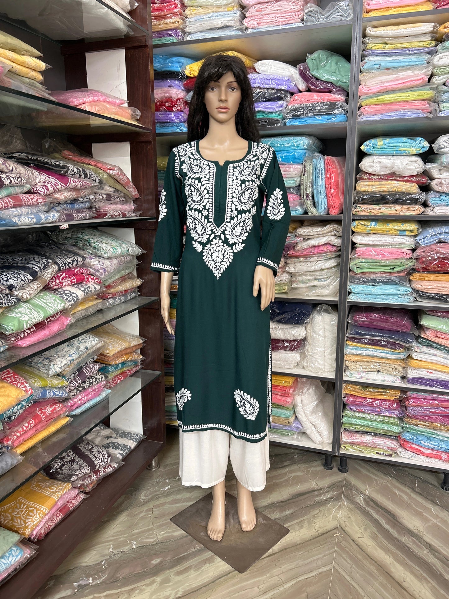 Mannequin wearing a green and white embroidered dress in a fabric store.