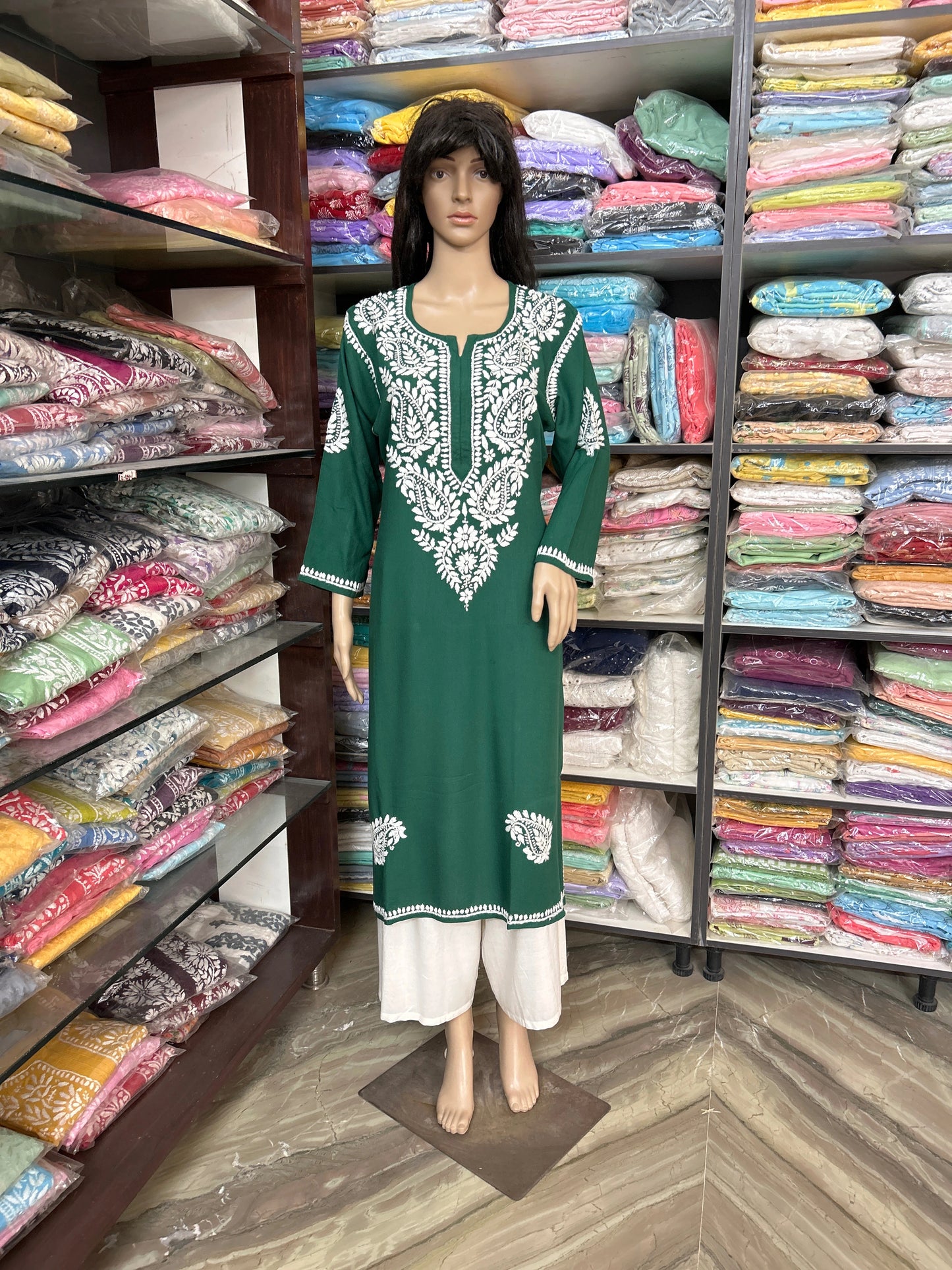 Lucknowi chikankari Mannequin wearing a green and white dress in a fabric store.