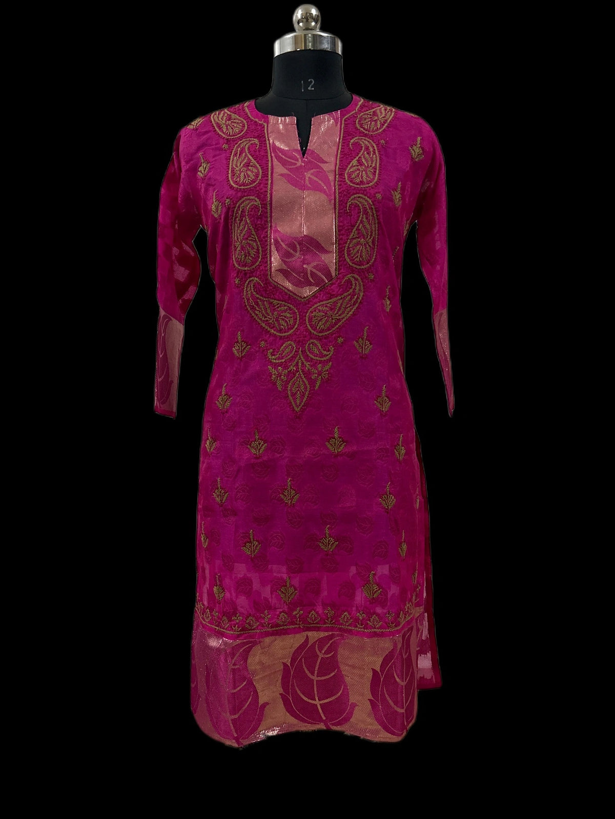 A magenta pink kurta with gold paisley and floral embroidery, displayed on a black dress form mannequin against a solid black background.