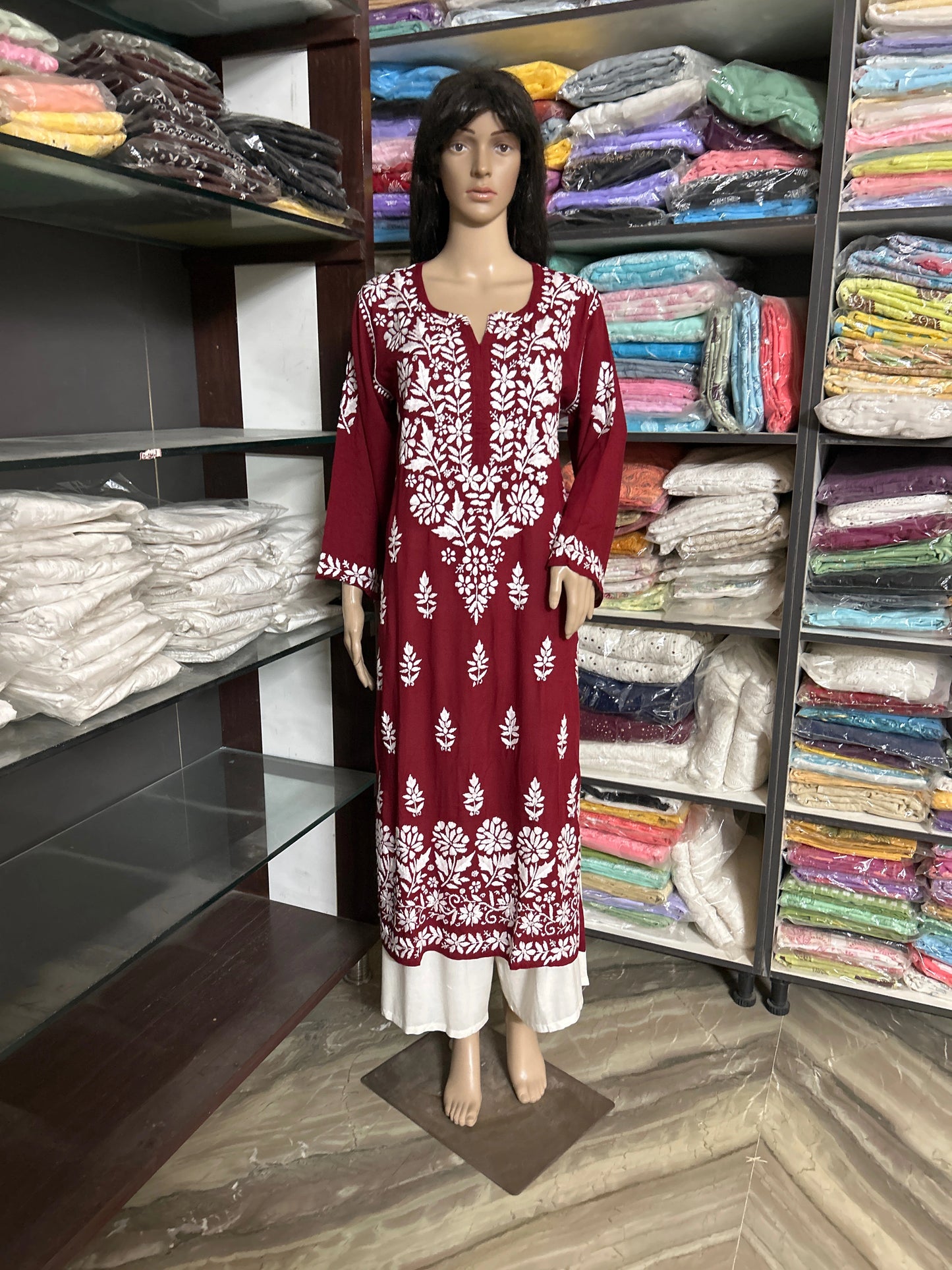 Lucknowi chikankari Mannequin wearing a red and white patterned dress in a fabric store.