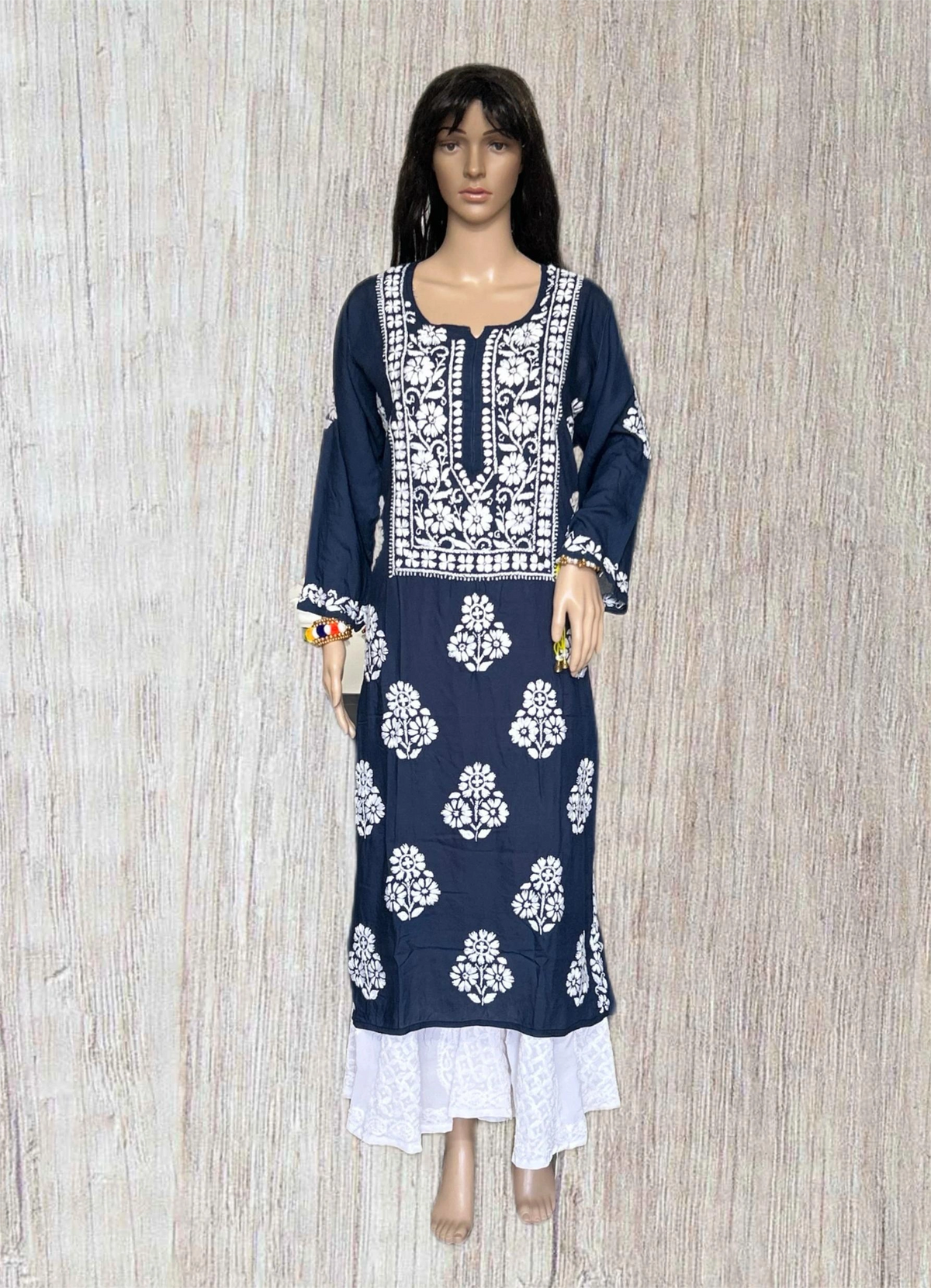 lucknowi chikankari Mannequin wearing a navy blue dress with white patterns in a fabric store.