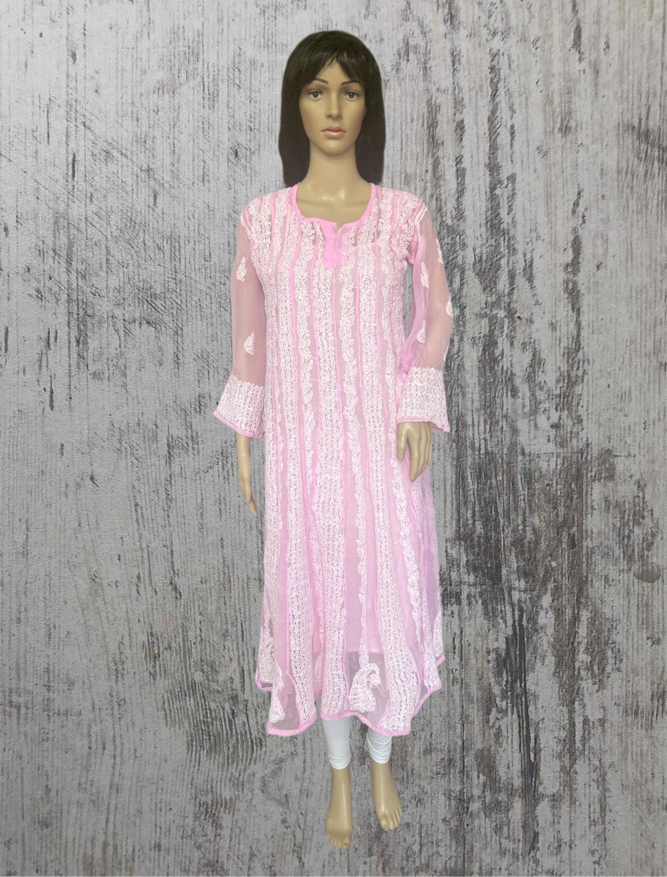 Mannequin wearing a lucknowi pink and white patterned dress on a textured gray background
