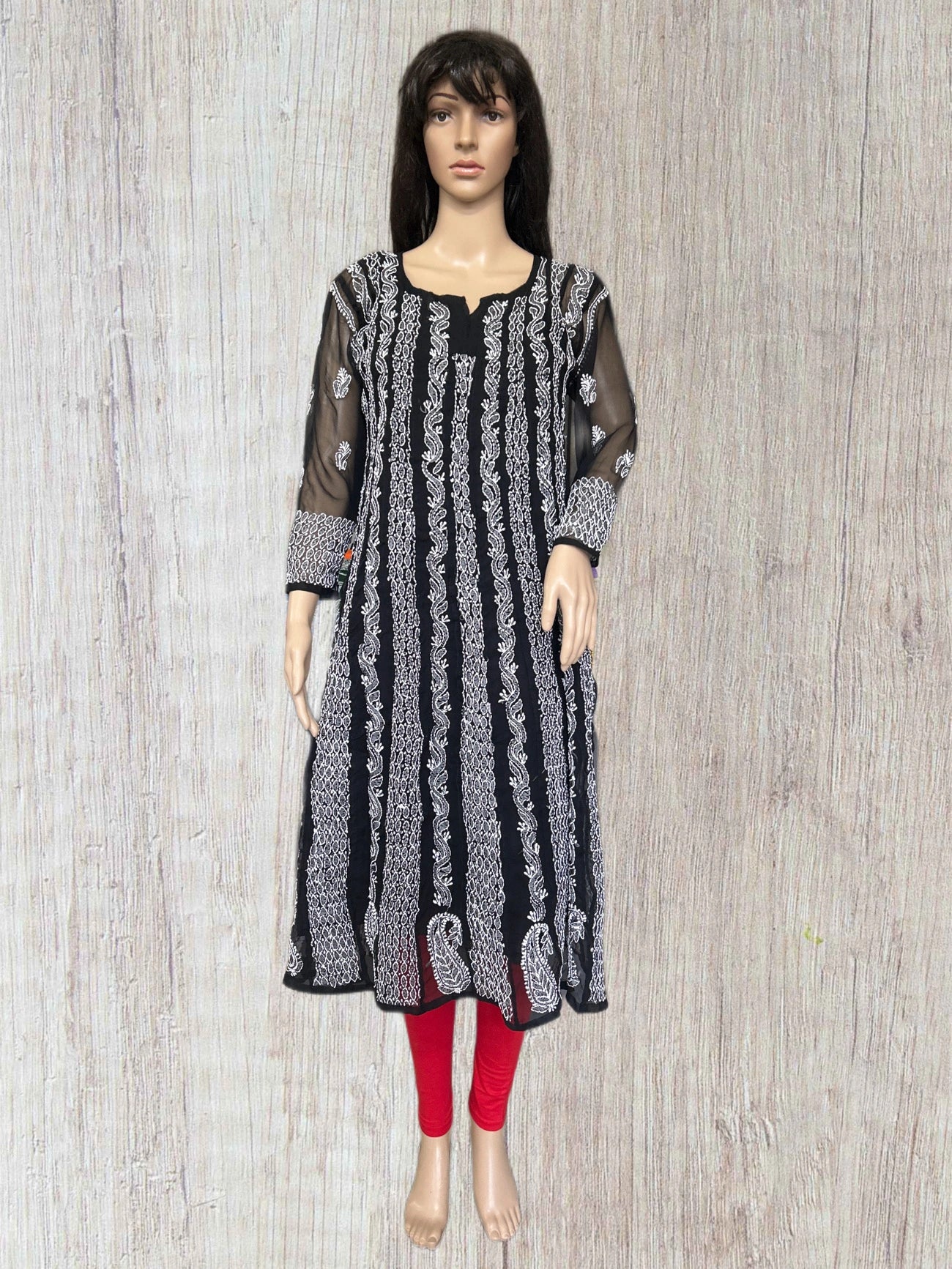 lucknowi chikankari Mannequin wearing a black and white patterned dress with red leggings on a wooden surface