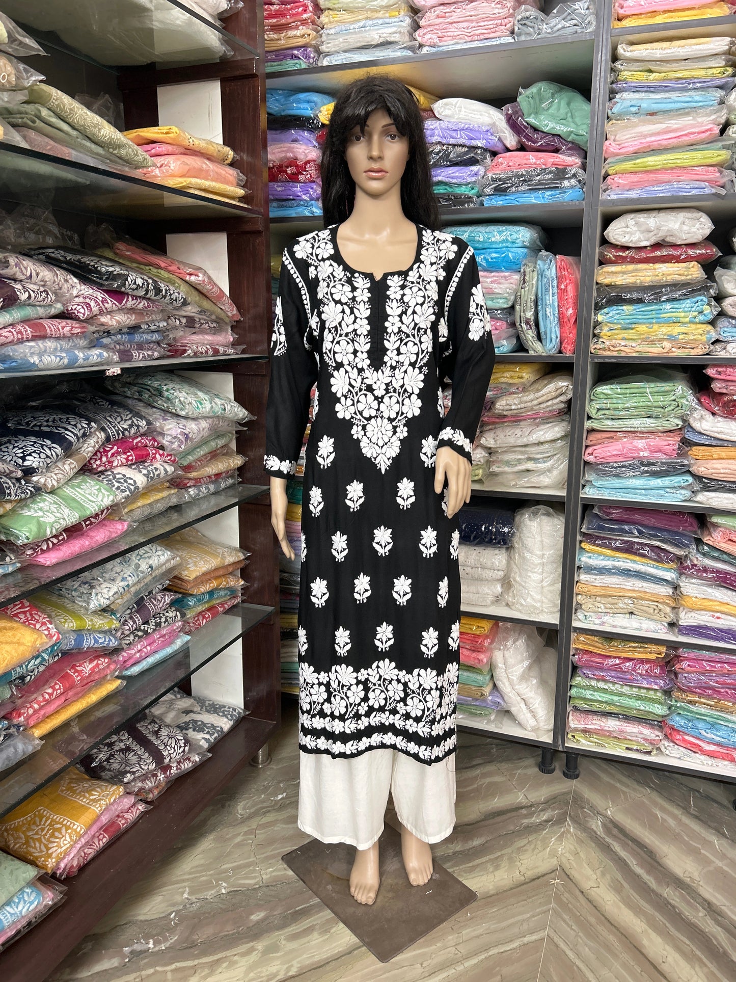 Mannequin wearing a black and white embroidered dress in a fabric store.