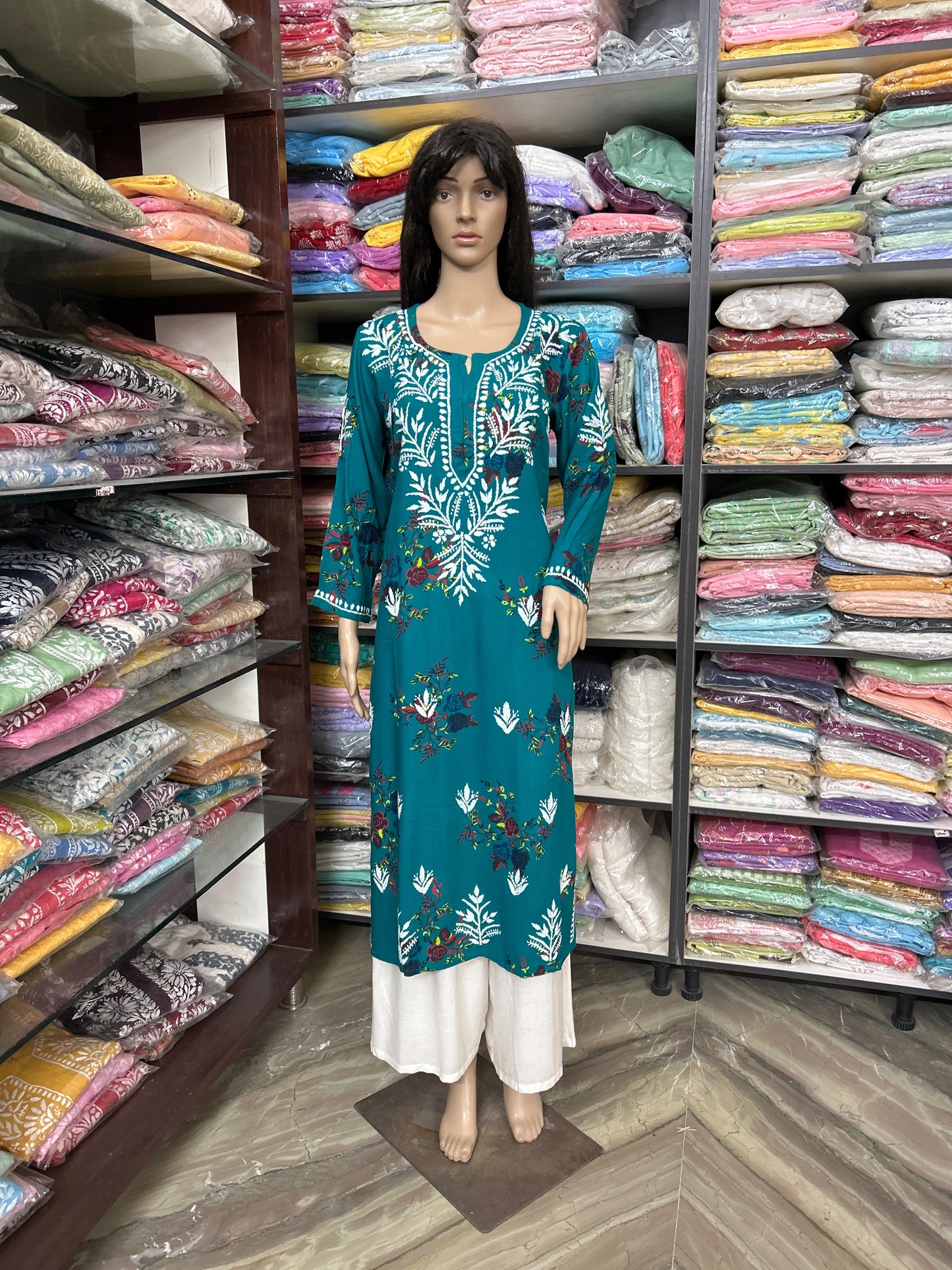Mannequin wearing a teal embroidered dress in a fabric store