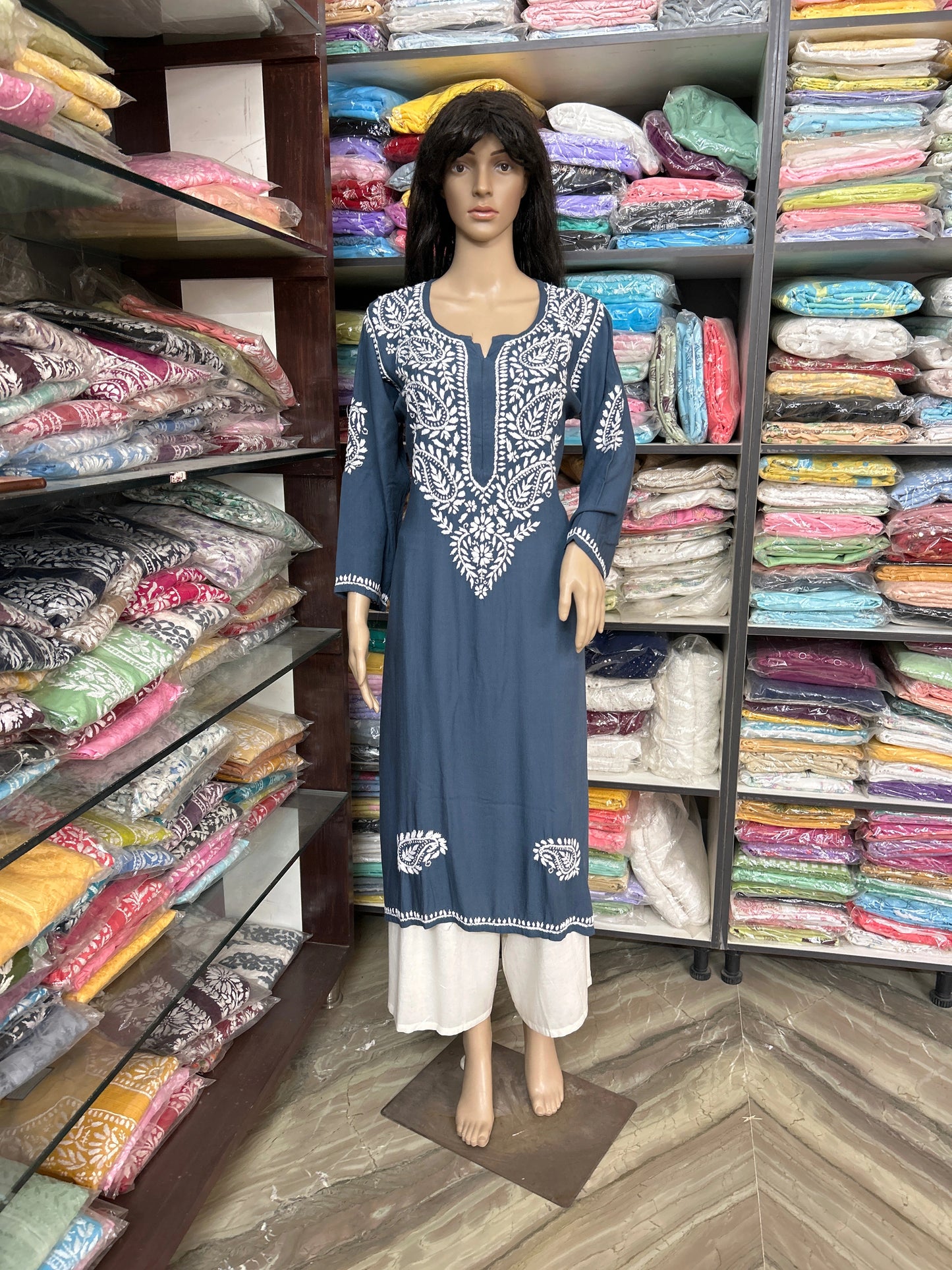 Mannequin wearing a blue embroidered dress in a fabric store