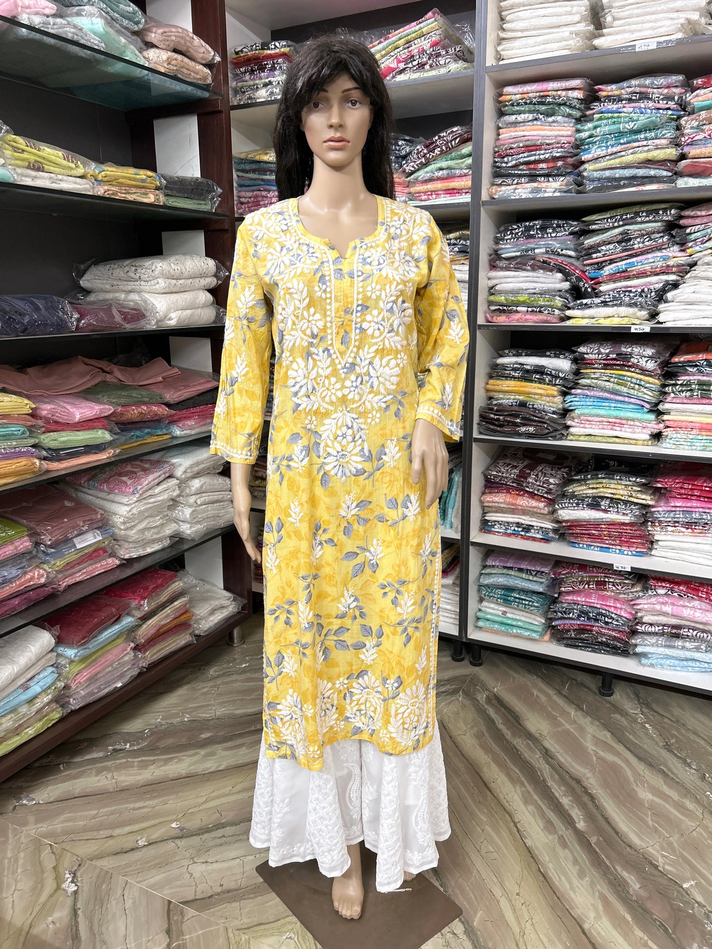 Mannequin wearing a lucknowi chikankari yellow floral dress in a fabric store