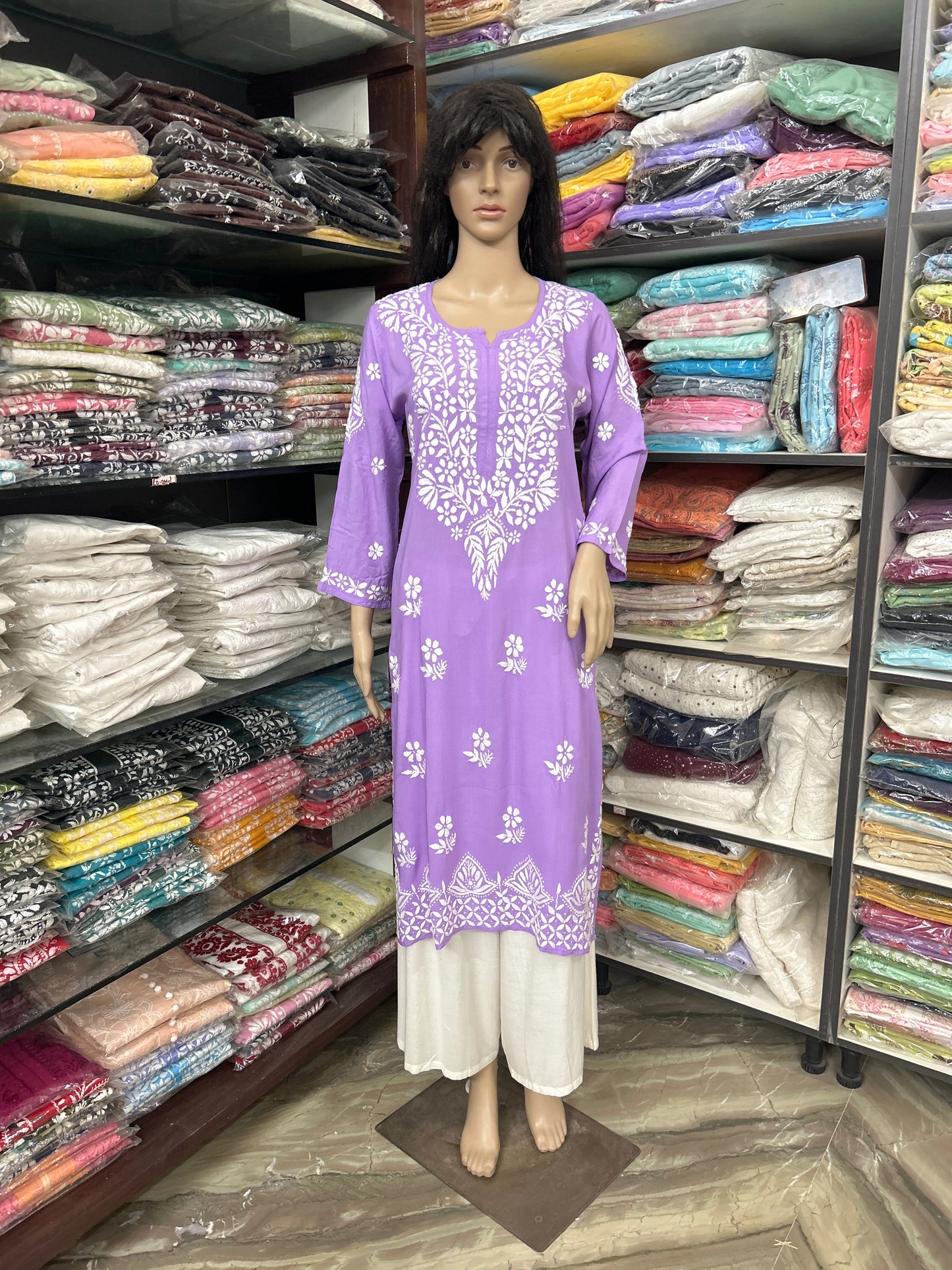 lucknowi chikankari Mannequin wearing a purple dress with floral patterns in a fabric store.