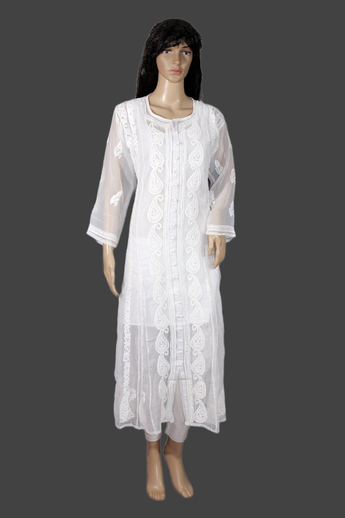 A white embroidered kurta set displayed on a female mannequin against a dark gray background. The outfit features a long-sleeved sheer embroidered outer layer over a matching white inner dress and pants.