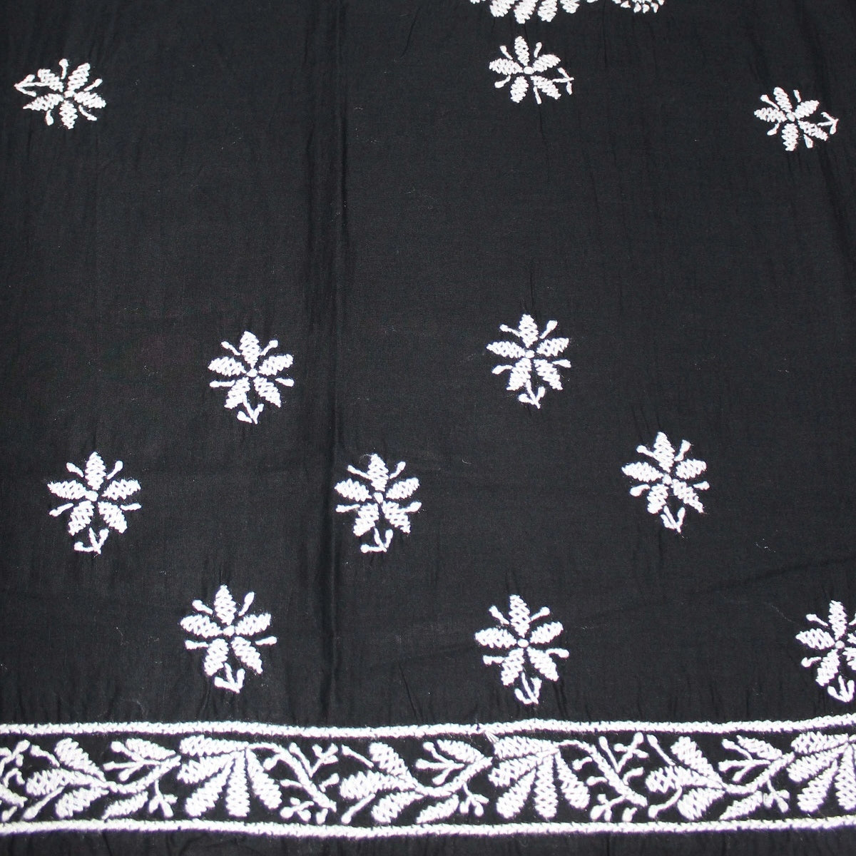 Black fabric with white floral patterns and a decorative border.