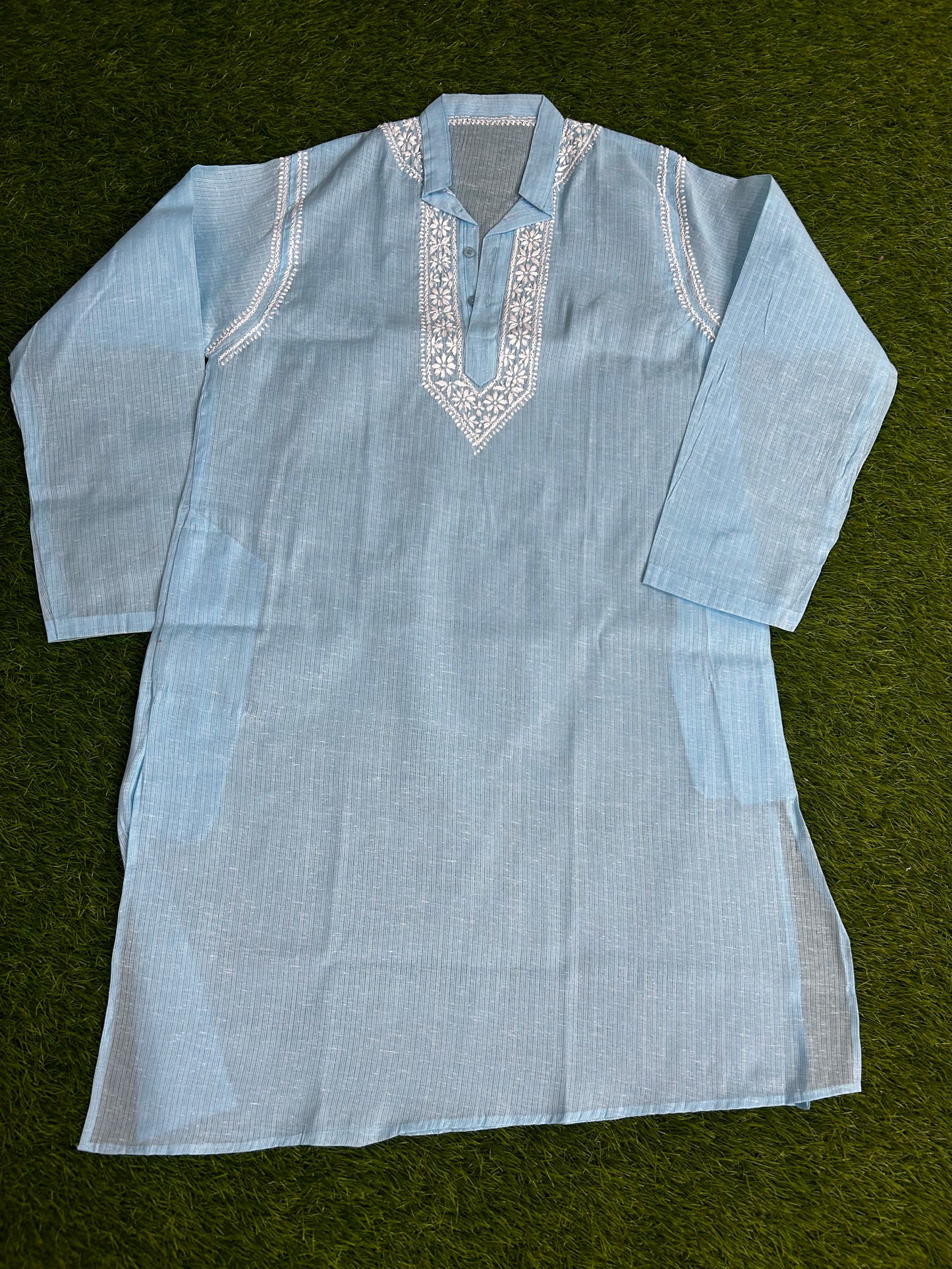 Light blue embroidered shirt on a green background