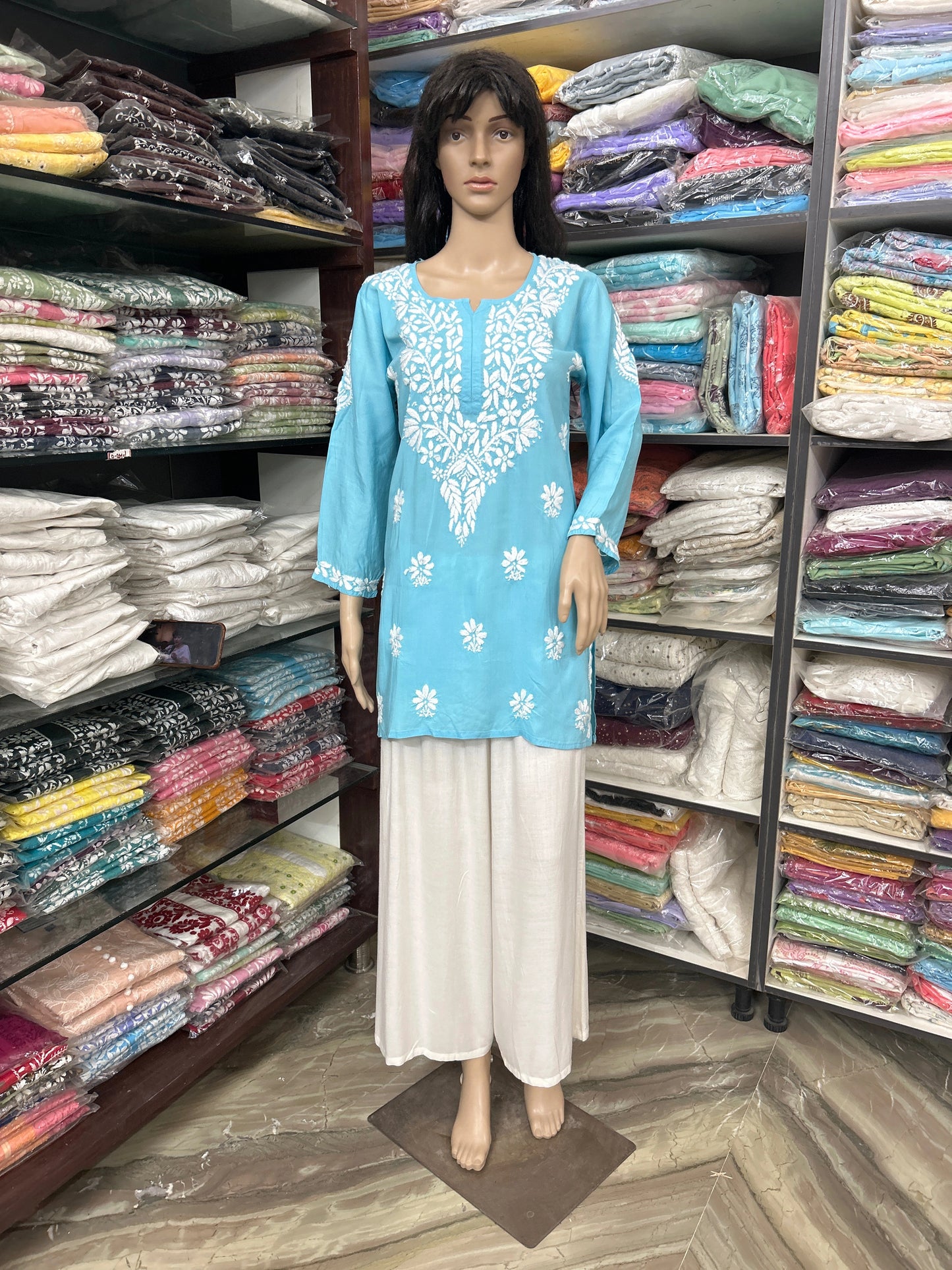 Mannequin wearing a lucknowi chikankari blue top in a fabric store.