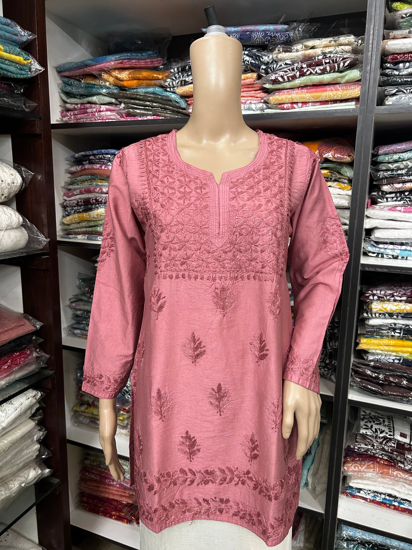Mannequin wearing a pink embroidered dress in a fabric store.