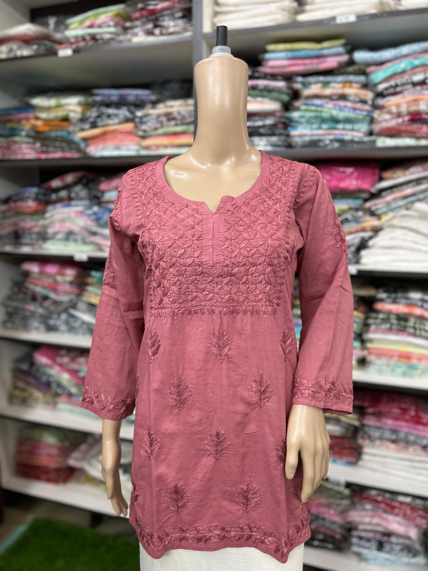 Mannequin wearing a pink embroidered top in a fabric store
