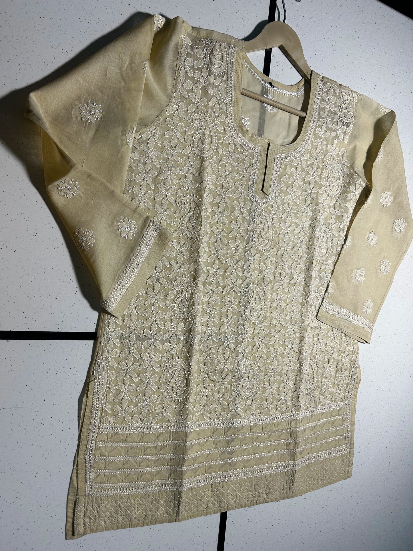 Beige embroidered kurta on a hanger against a white background