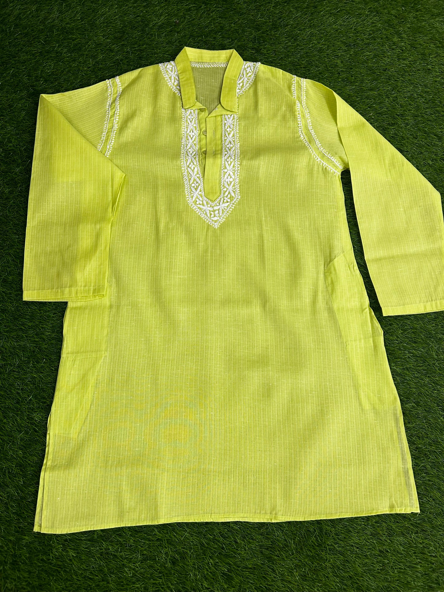 Light green traditional outfit with white embroidery on a dark green background