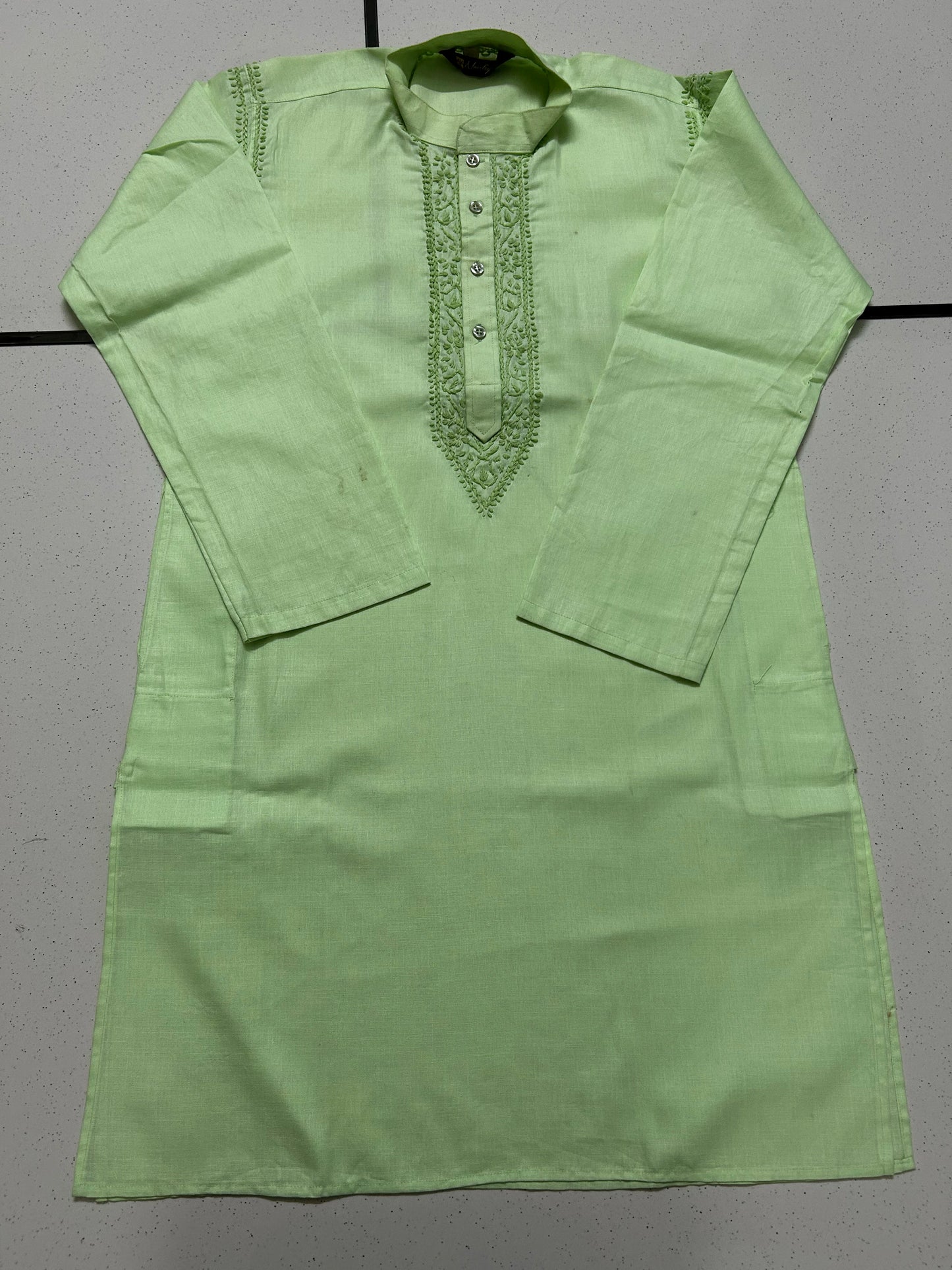 Green kurta with intricate embroidery on a gray background