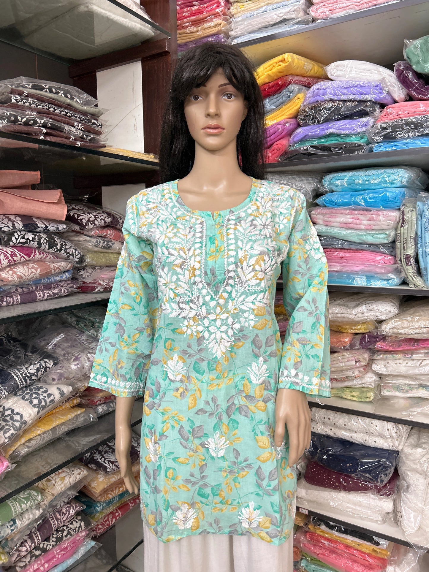 lucknowi chikankari Mannequin wearing a light blue floral dress in a fabric store.
