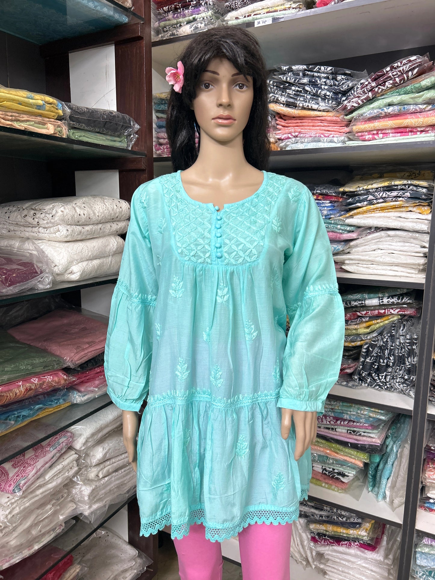 Mannequin wearing a lucknowi chikankari light blue dress with pink leggings in a fabric store.