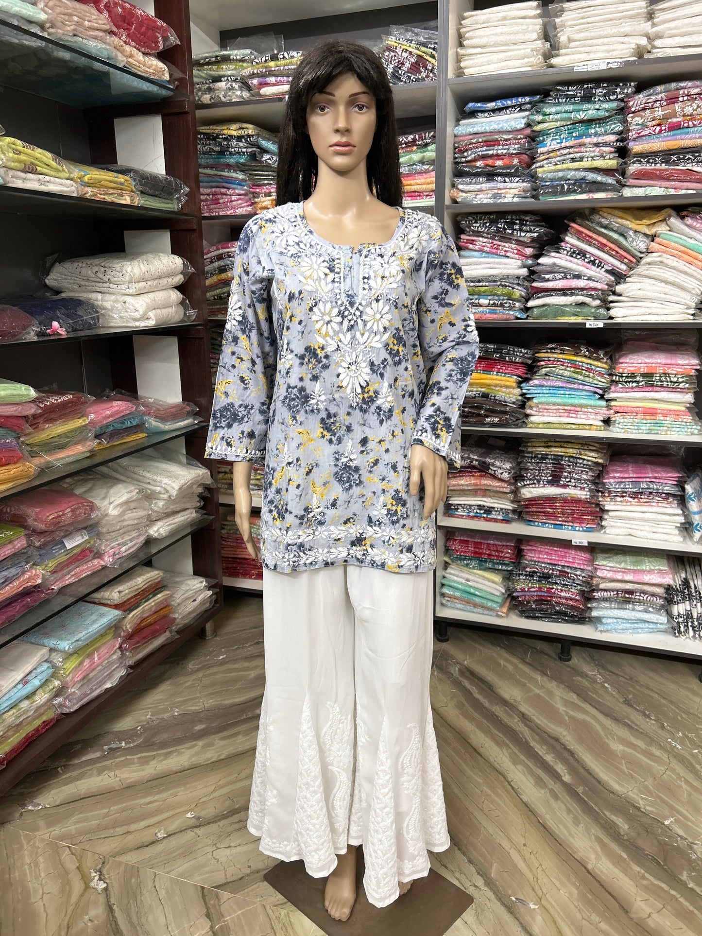 Mannequin wearing a lucknowi chikankari floral top and white pants in a fabric store.