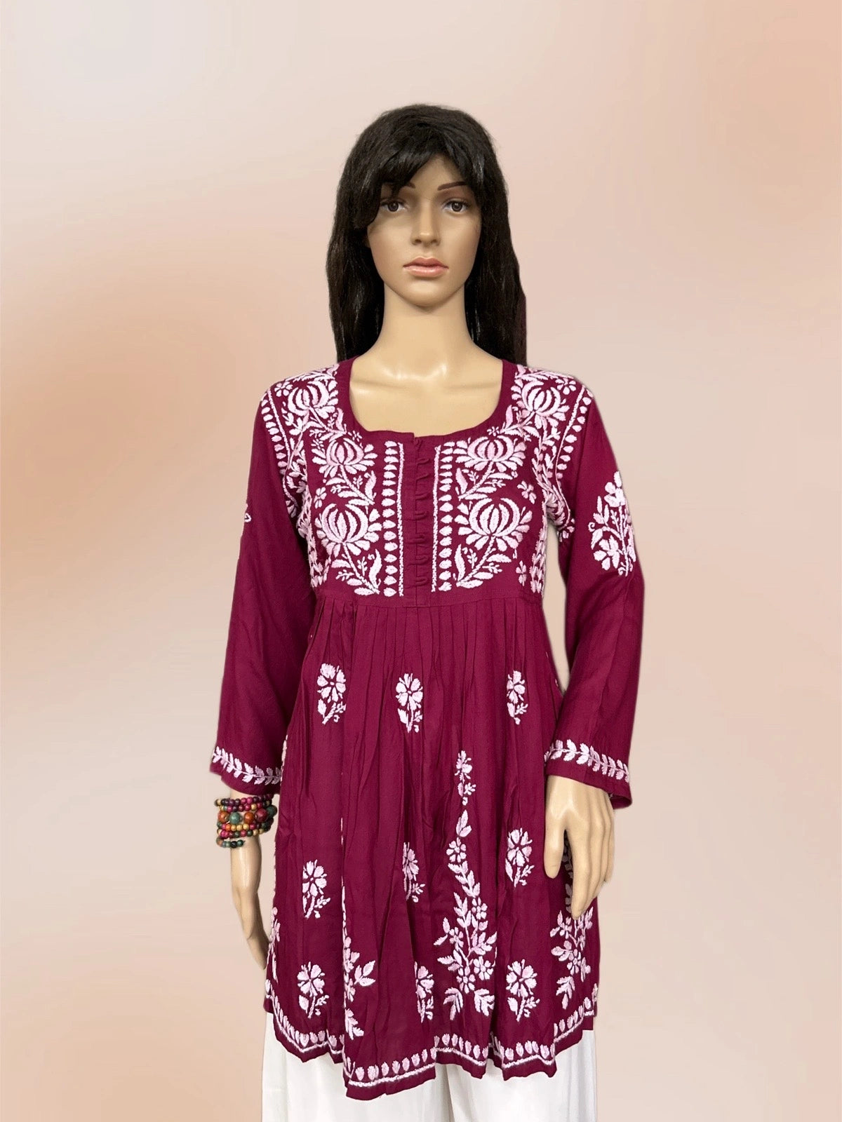 Maroon kurta with white floral embroidery on a gradient background