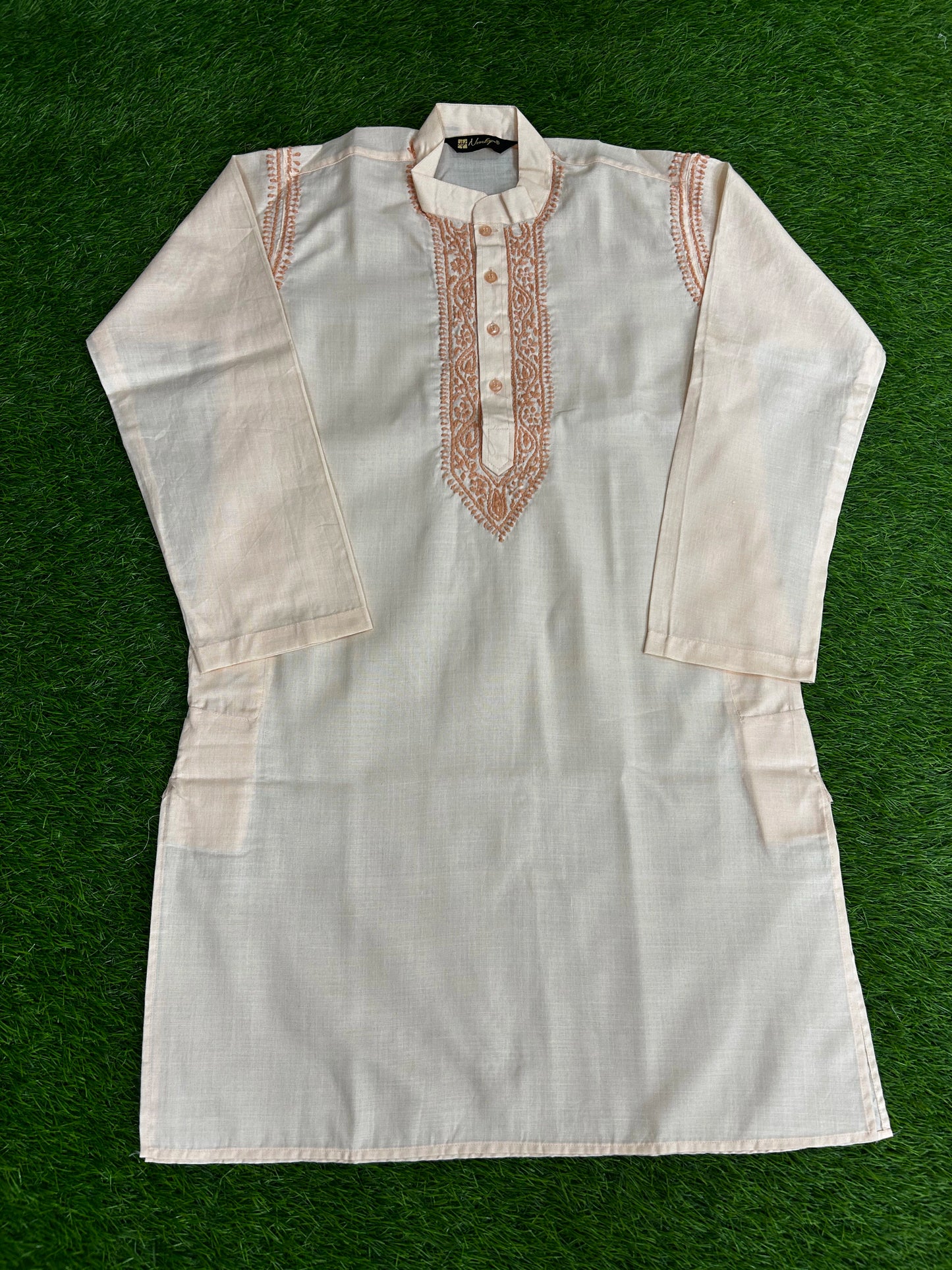 White kurta with intricate embroidery on a green background