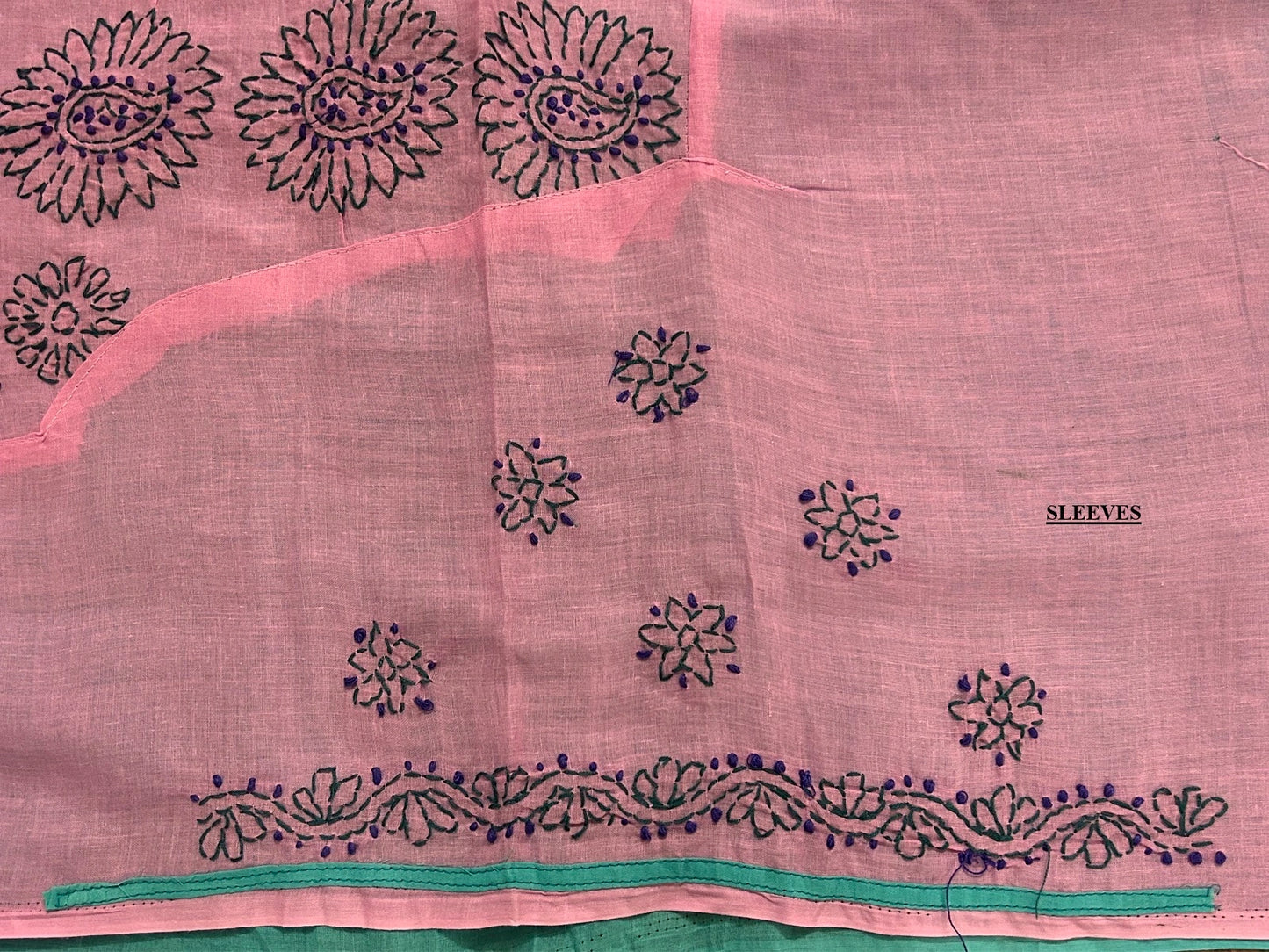 Pink fabric with black floral embroidery and green trim