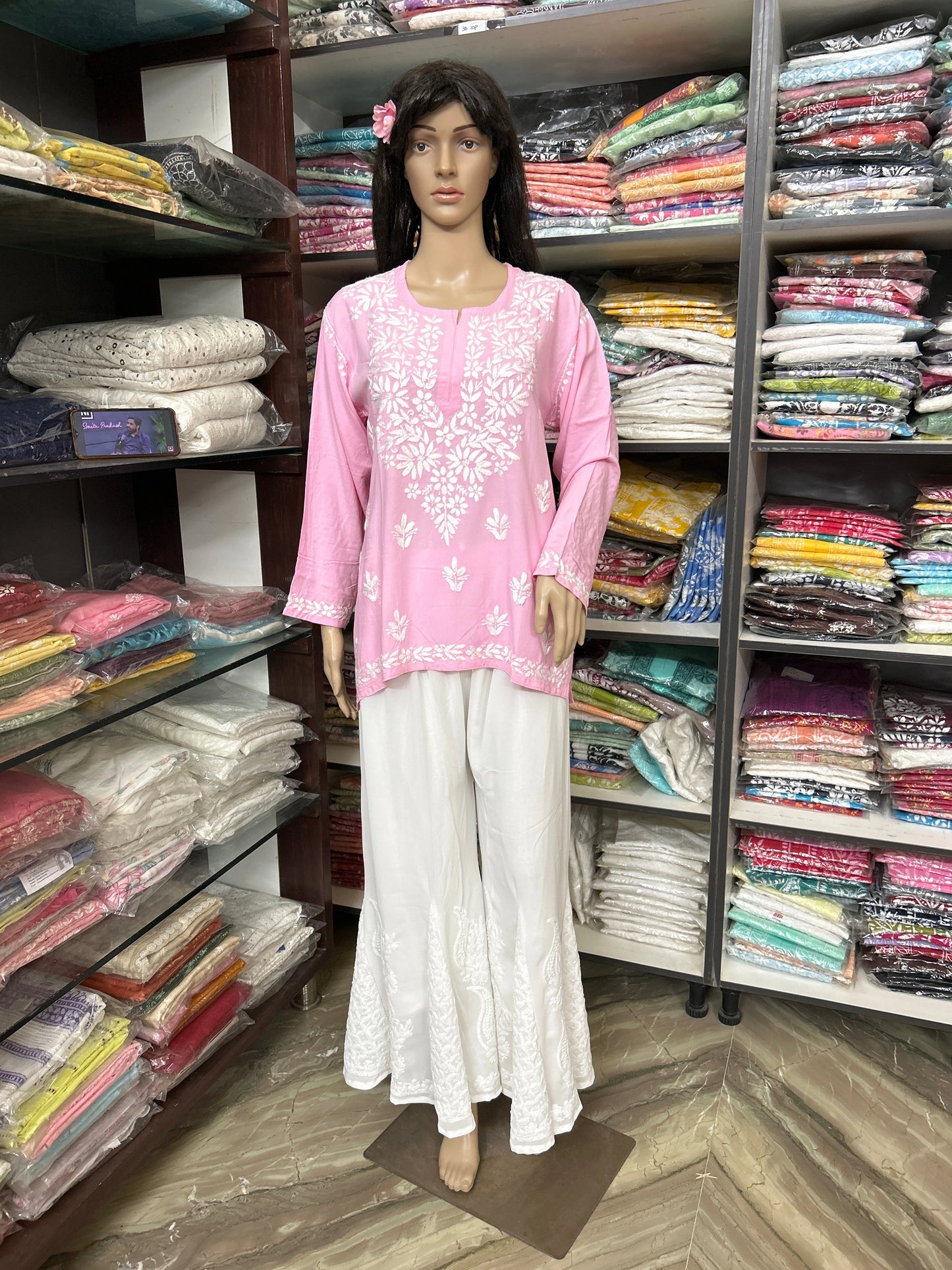 Mannequin wearing a lucknowi chikankari pink top and white pants in a fabric store.