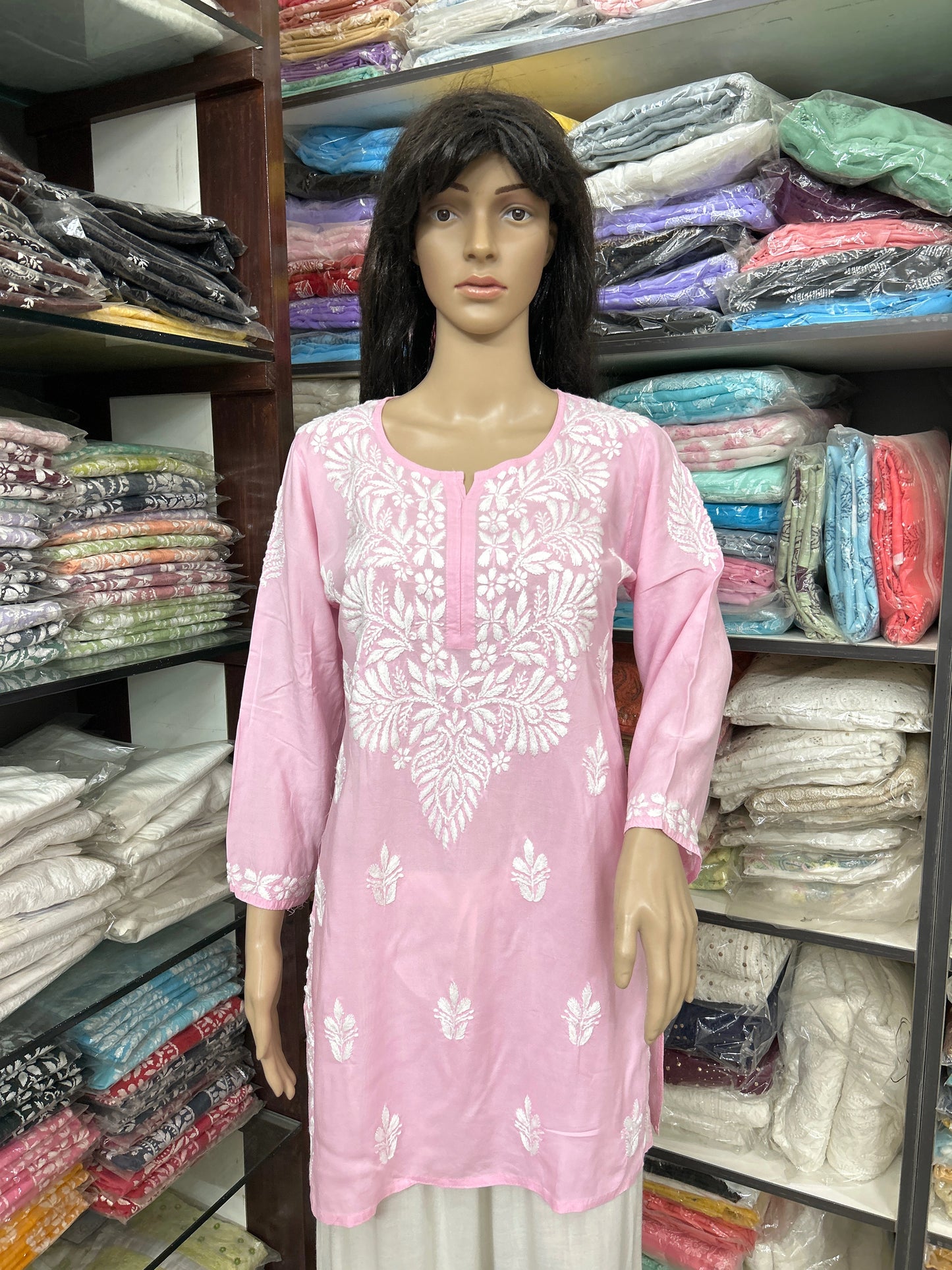 Mannequin wearing a pink embroidered kurta in a fabric store.