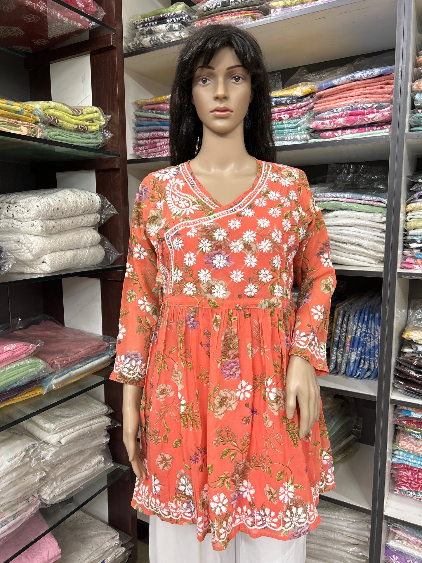 Mannequin wearing a lucknowi chikankari floral orange dress in a fabric store