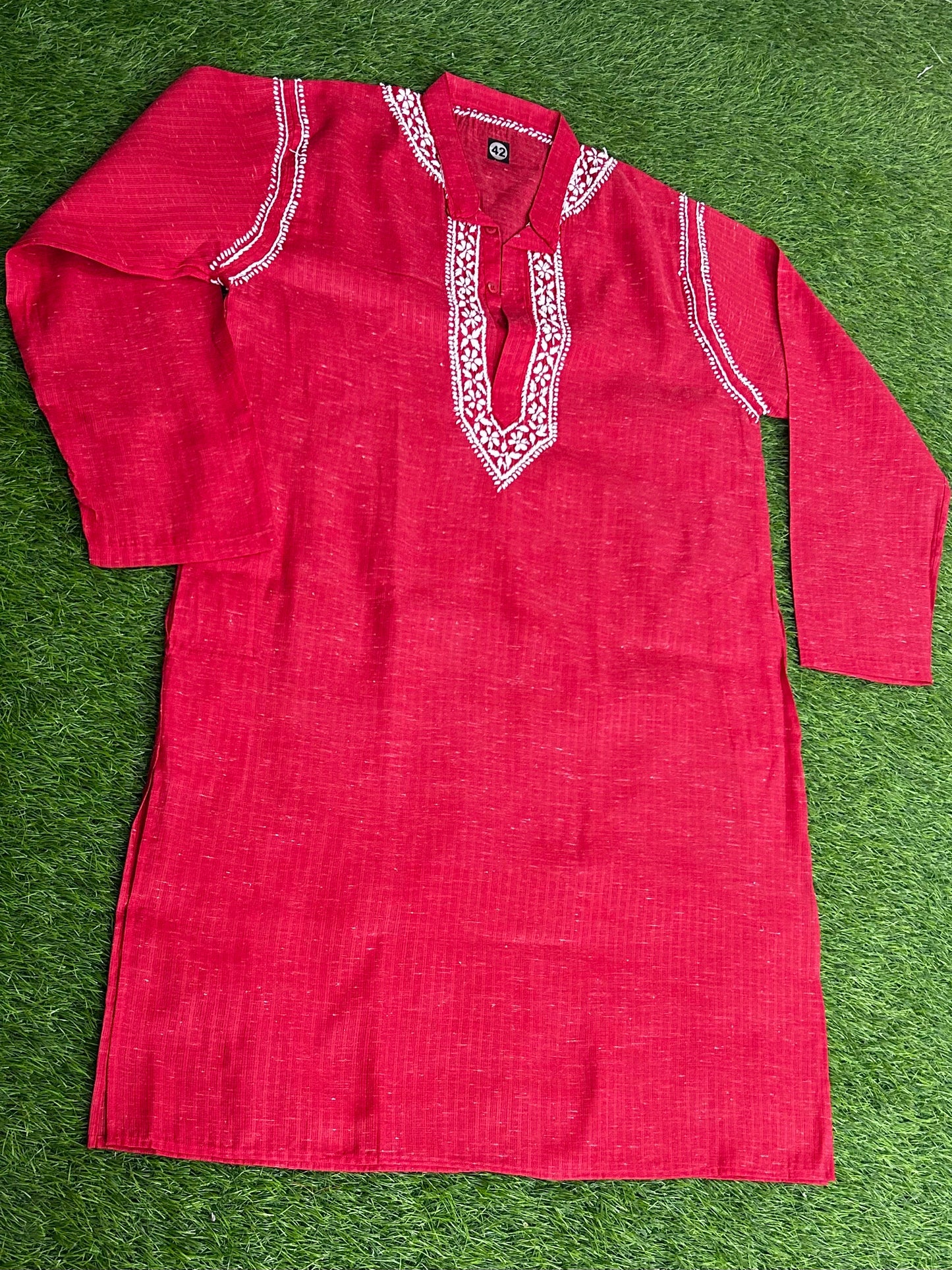 Red kurta with white embroidery on a green grass background