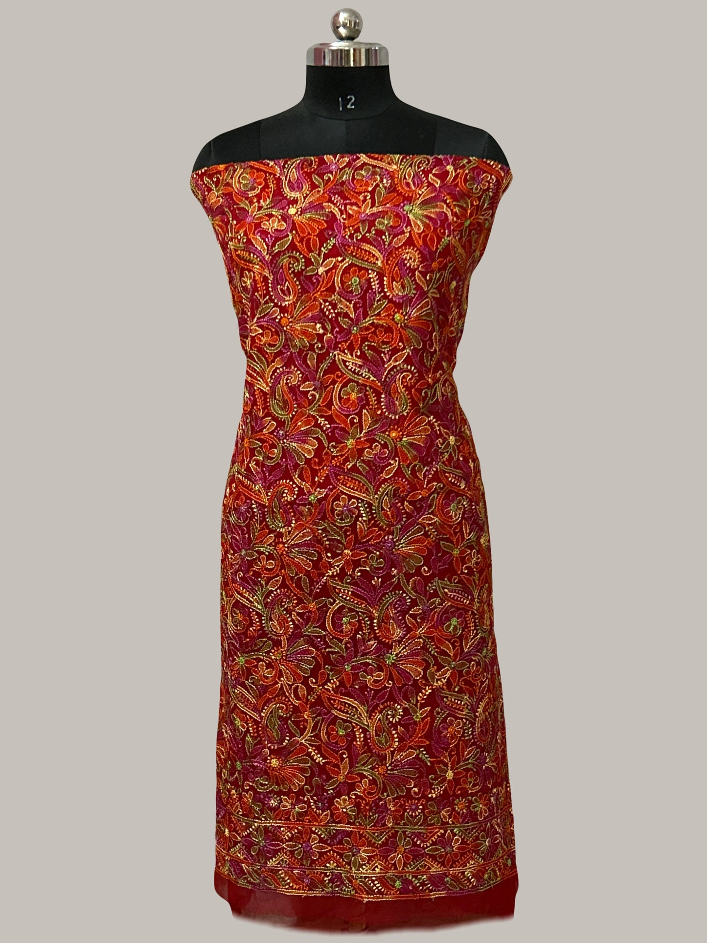 Lucknowi chikankari Mannequin wearing a red and gold patterned dress on a gray background