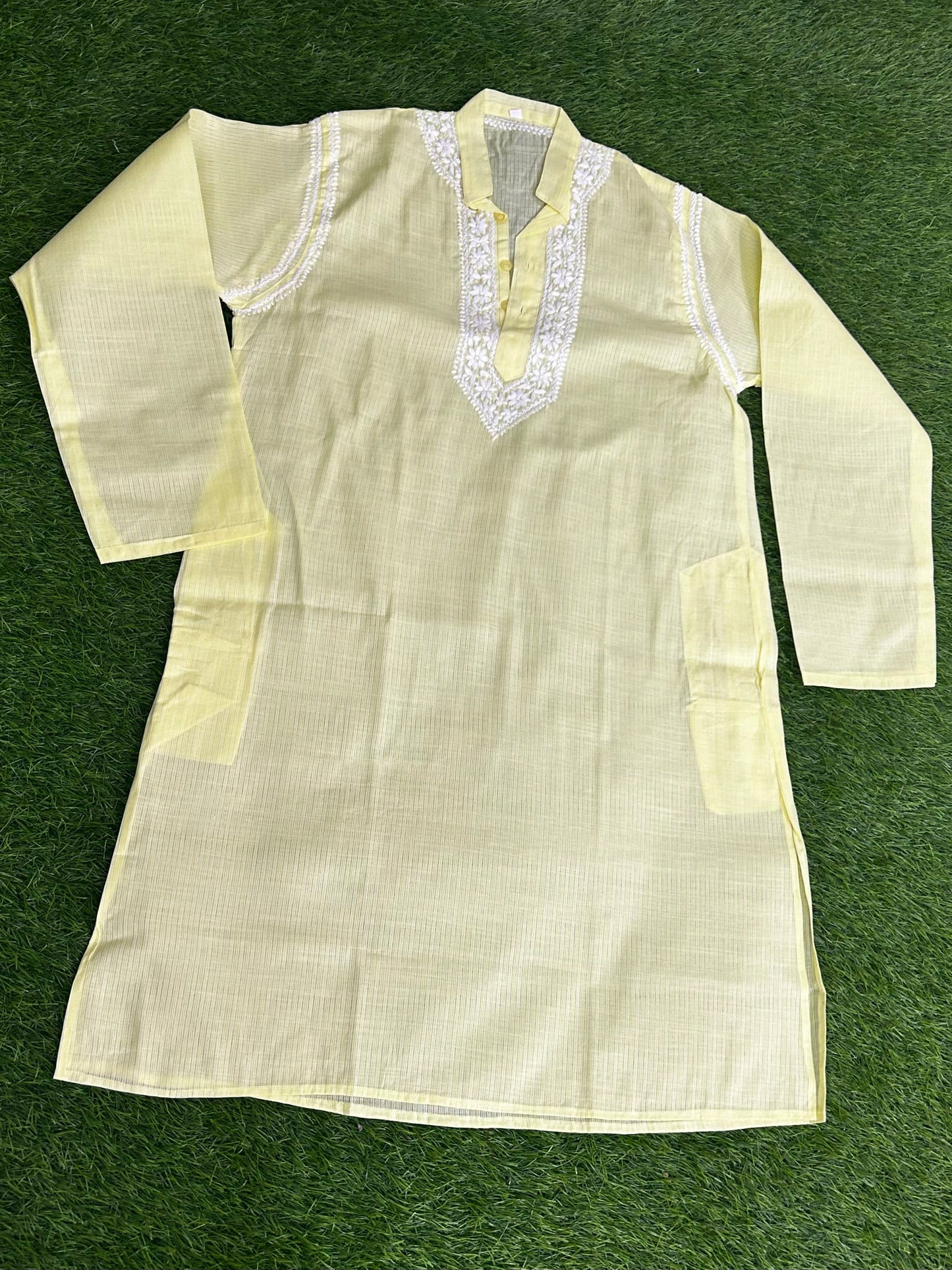 lucknowi chikankari Light-colored kurta with intricate detailing on a green background