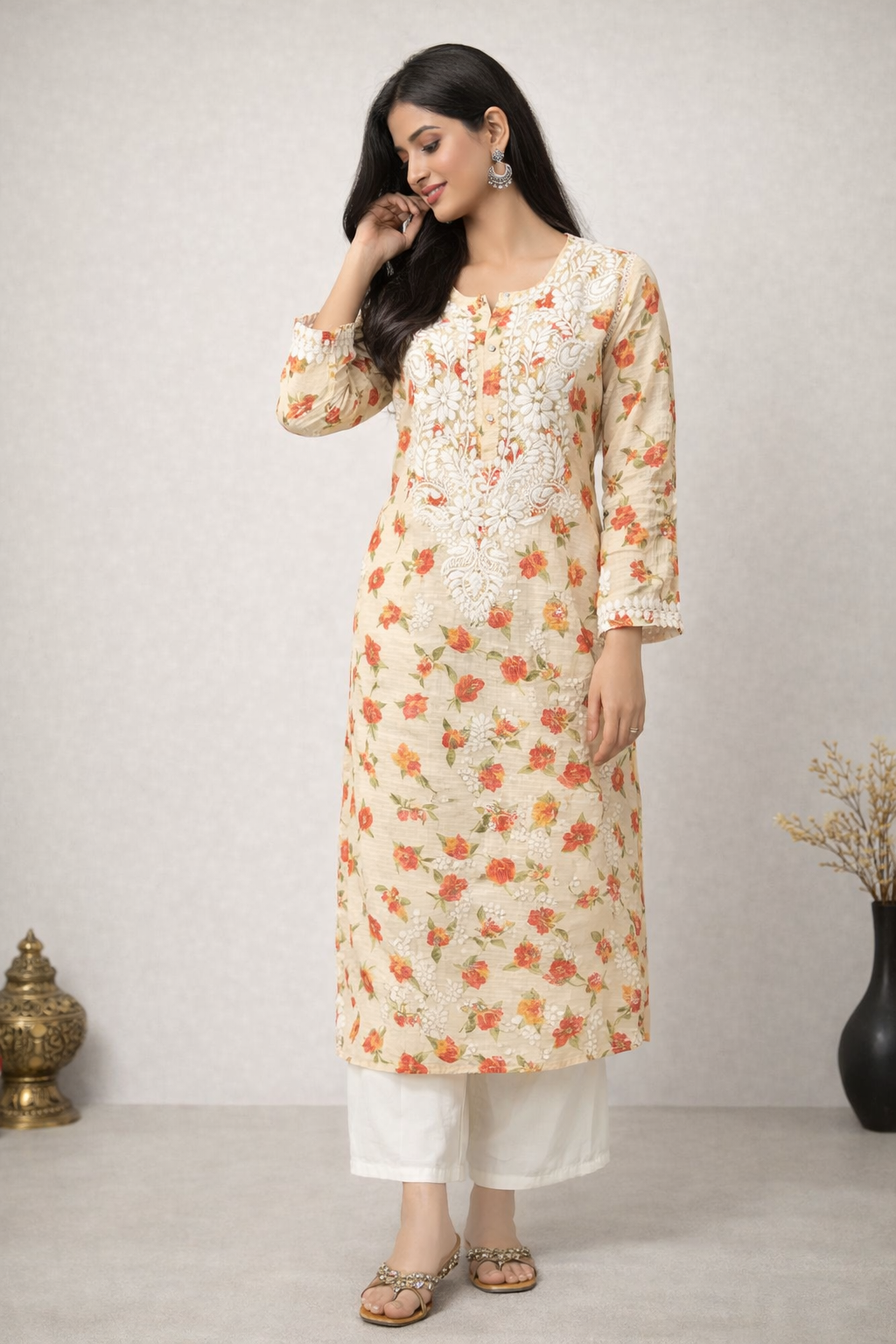 Woman wearing a floral kurta with white pants against a plain background
