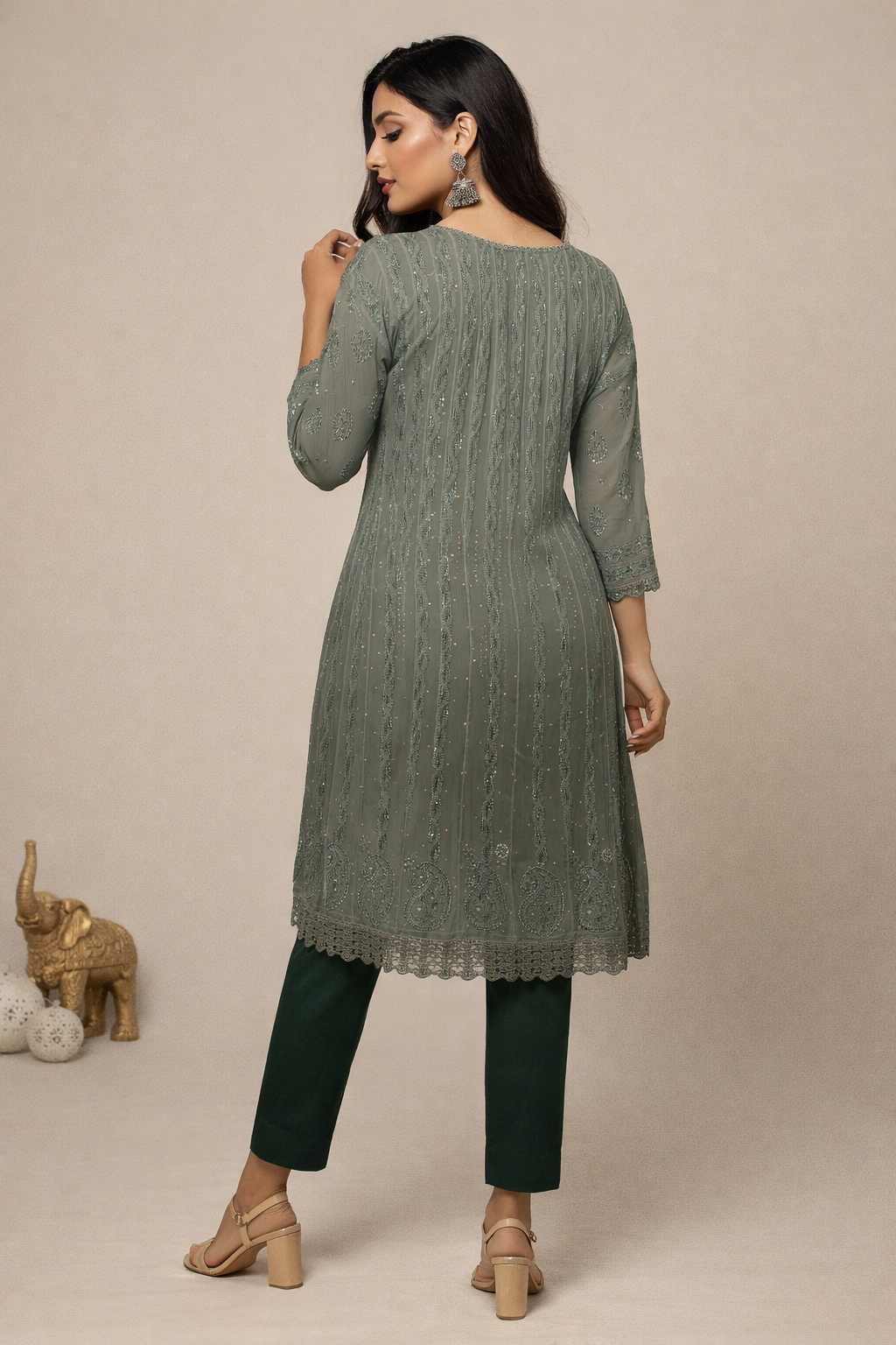 Woman wearing a green kurta with matching pants against a beige background