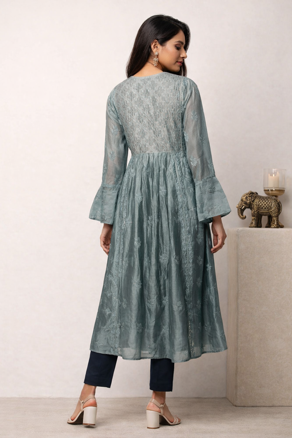Woman wearing a light blue kurta with bell sleeves in a minimalistic setting.