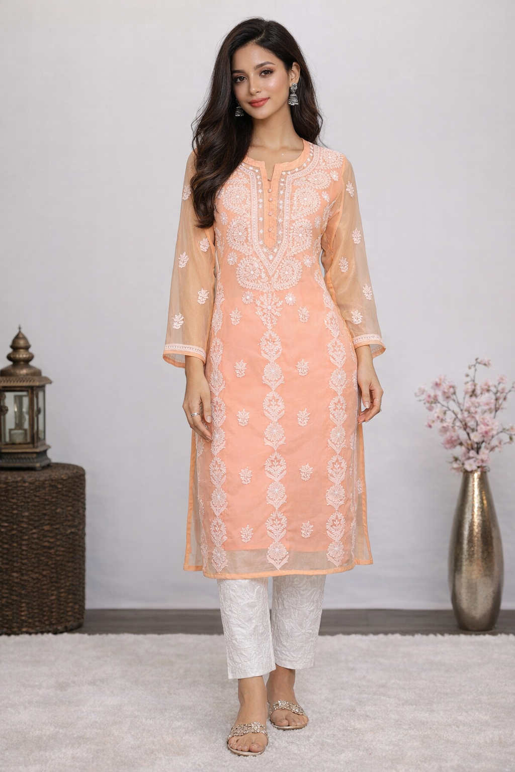 Woman wearing a peach embroidered kurta with white pants in a minimalistic setting.