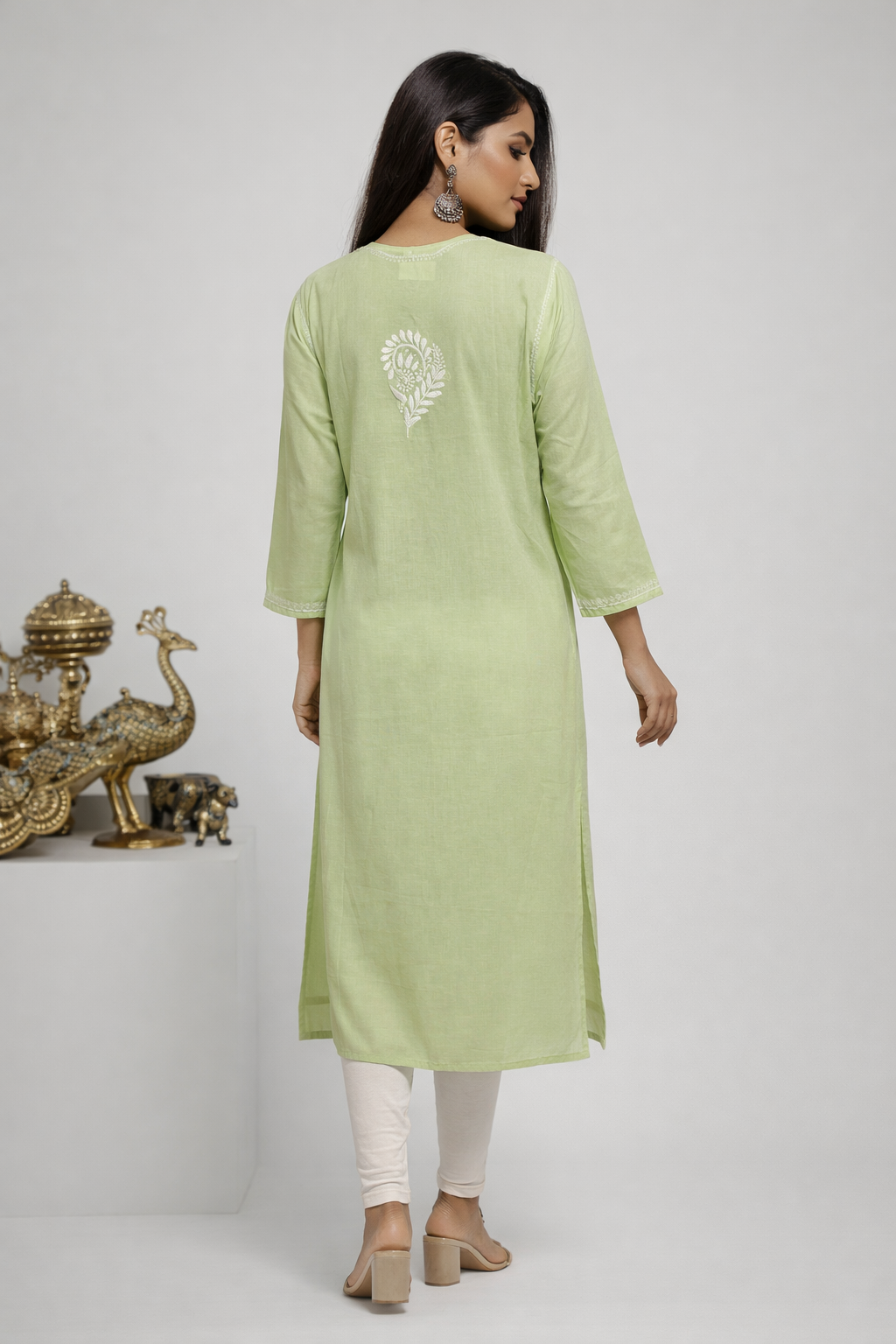 Woman wearing a light green kurta with white embroidery on a plain background
