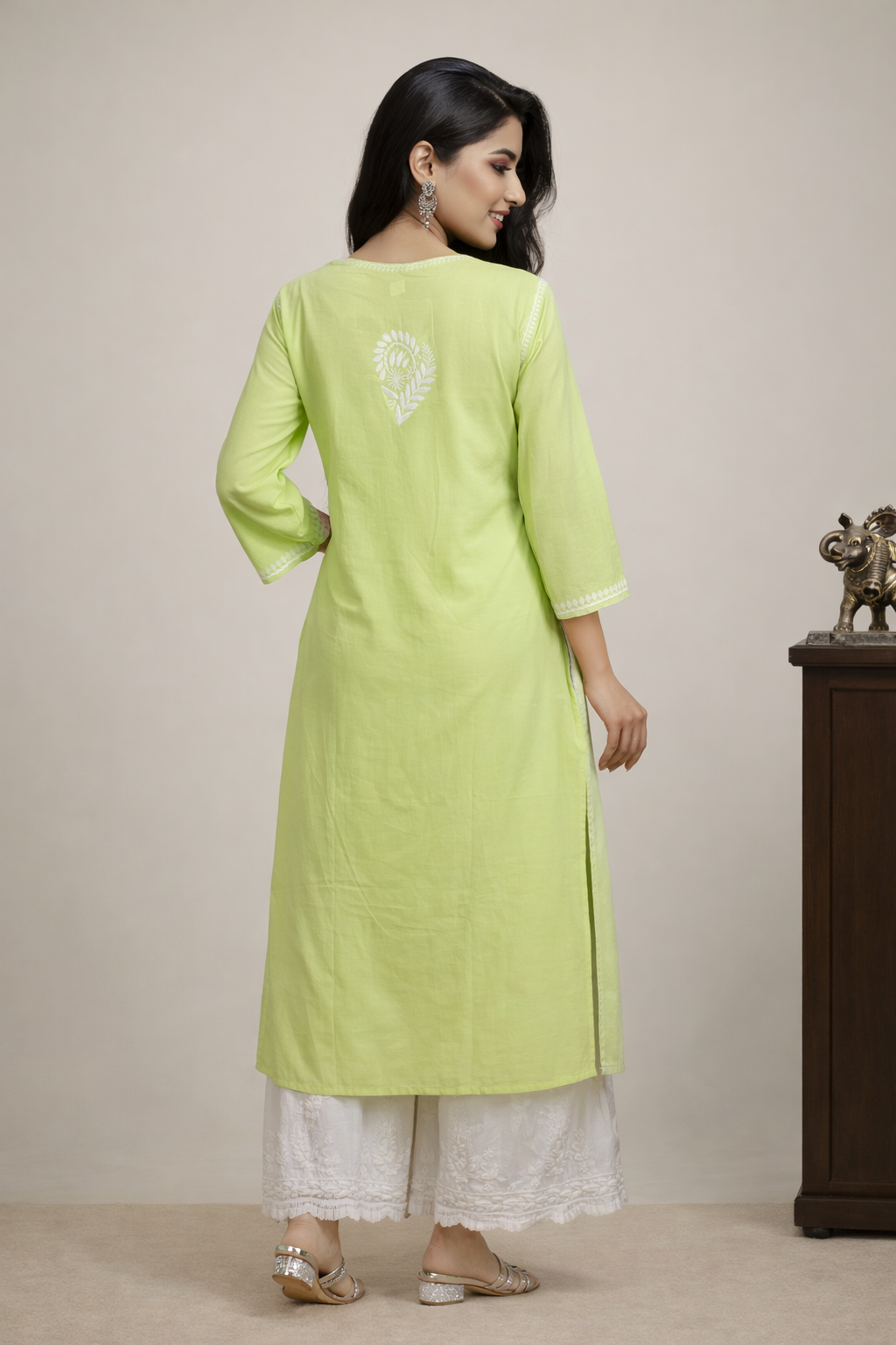 Woman wearing a light green kurta with white pants against a beige background