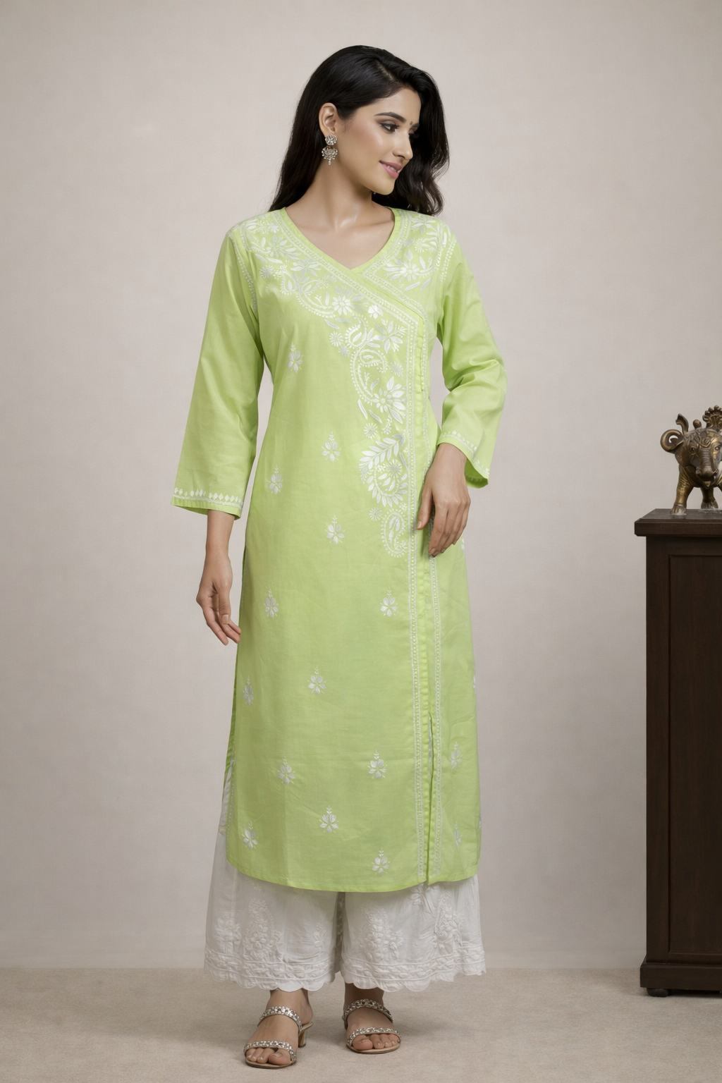 Woman wearing a light green kurta with white embroidery against a beige background