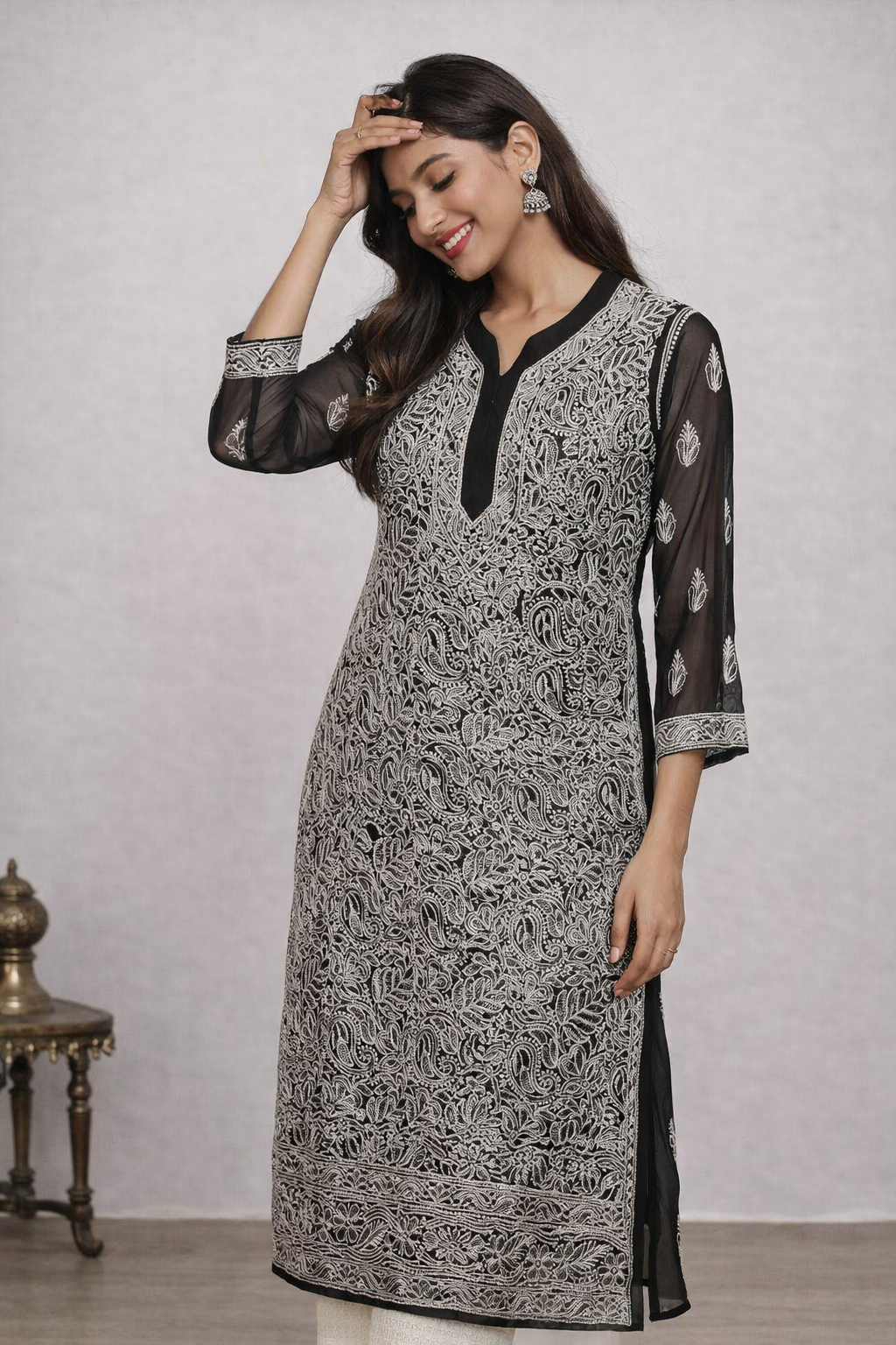 Woman wearing a black and white patterned kurta with sheer sleeves against a plain background