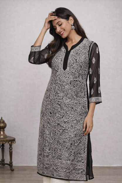Woman wearing a black and white patterned kurta with sheer sleeves against a plain background