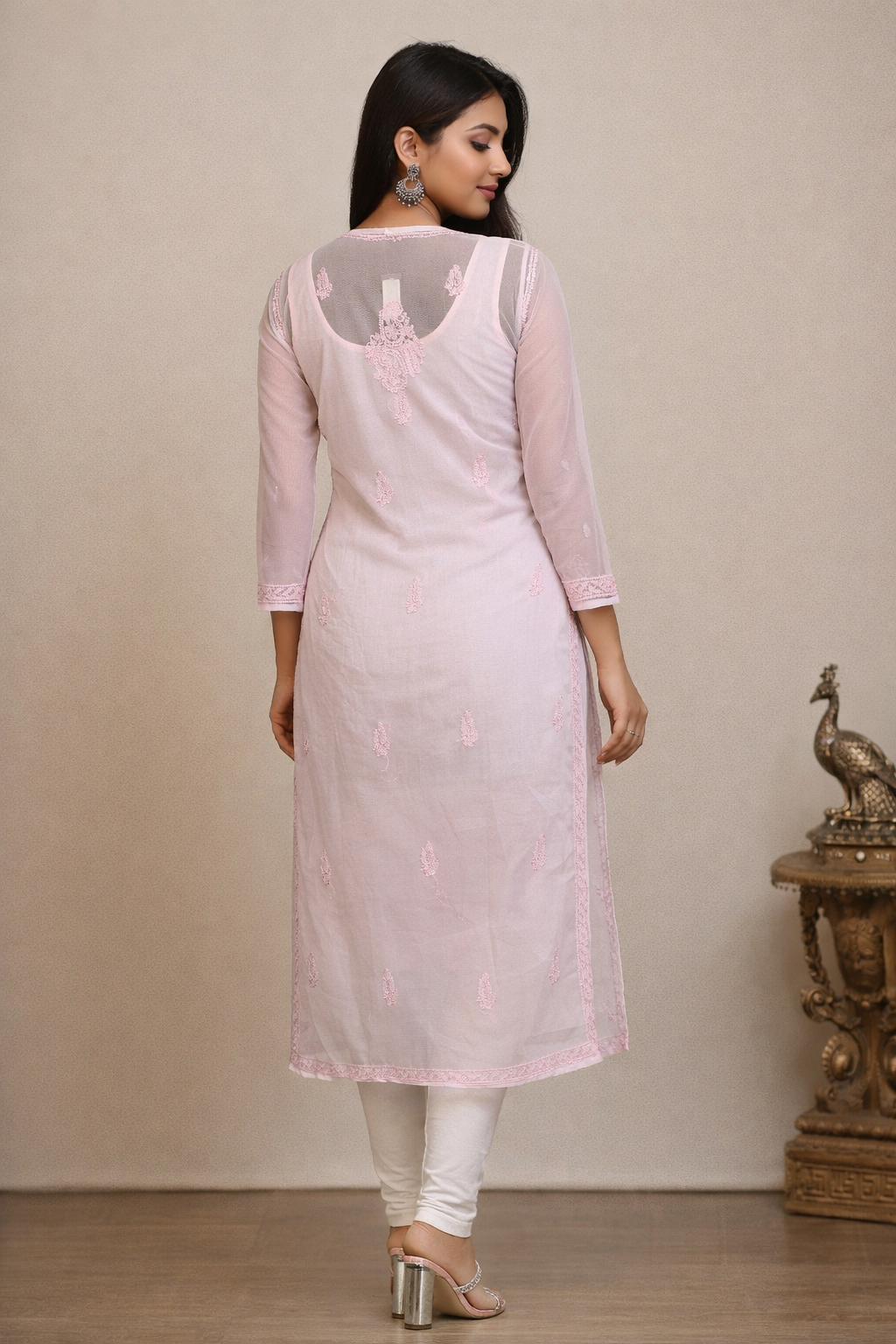 Woman wearing a light pink kurta with white pants against a beige background