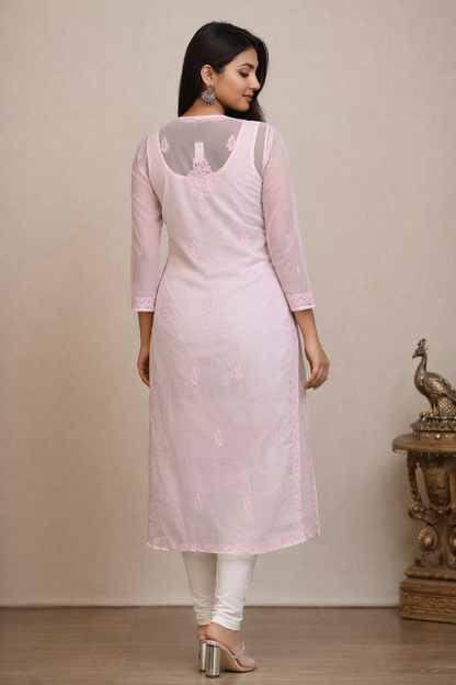 Woman wearing a light pink kurta with white pants against a beige background